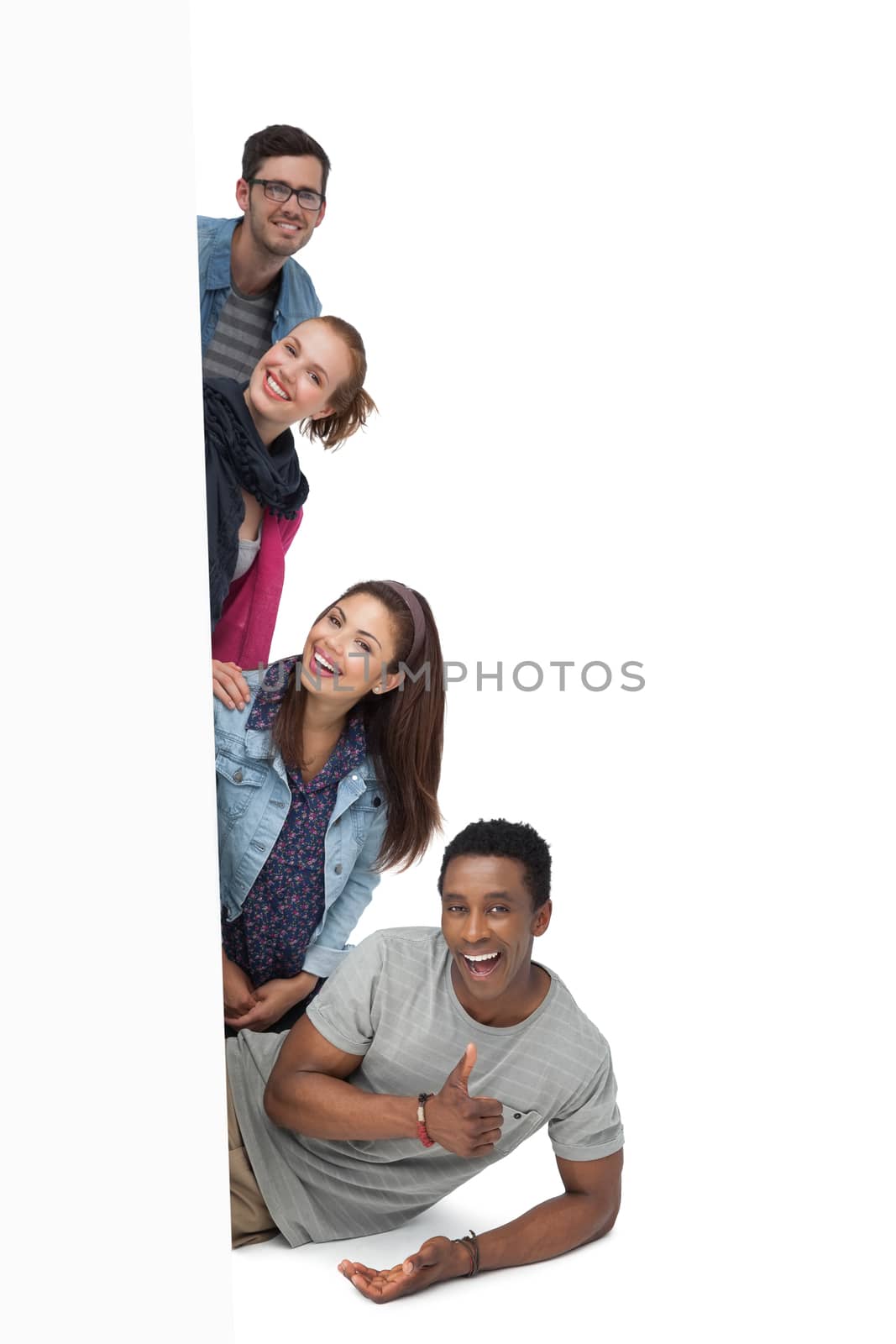 Portrait of four happy young friends with blank board by Wavebreakmedia