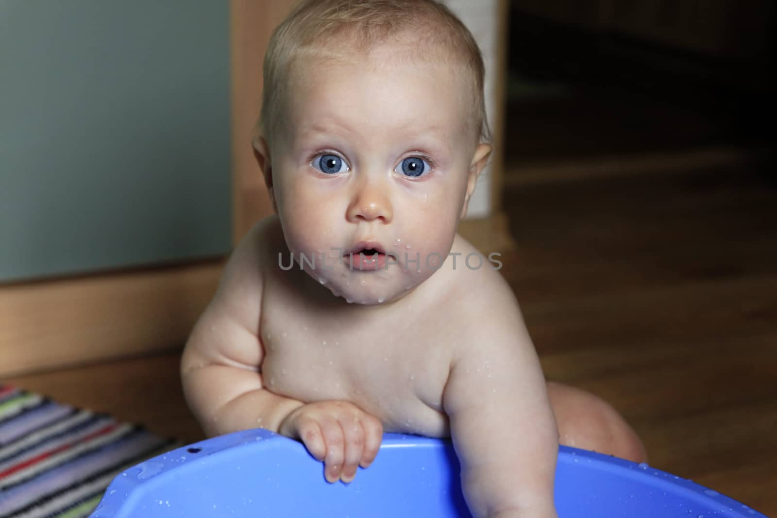 Portrait of a cute little girl playing with a blue basin