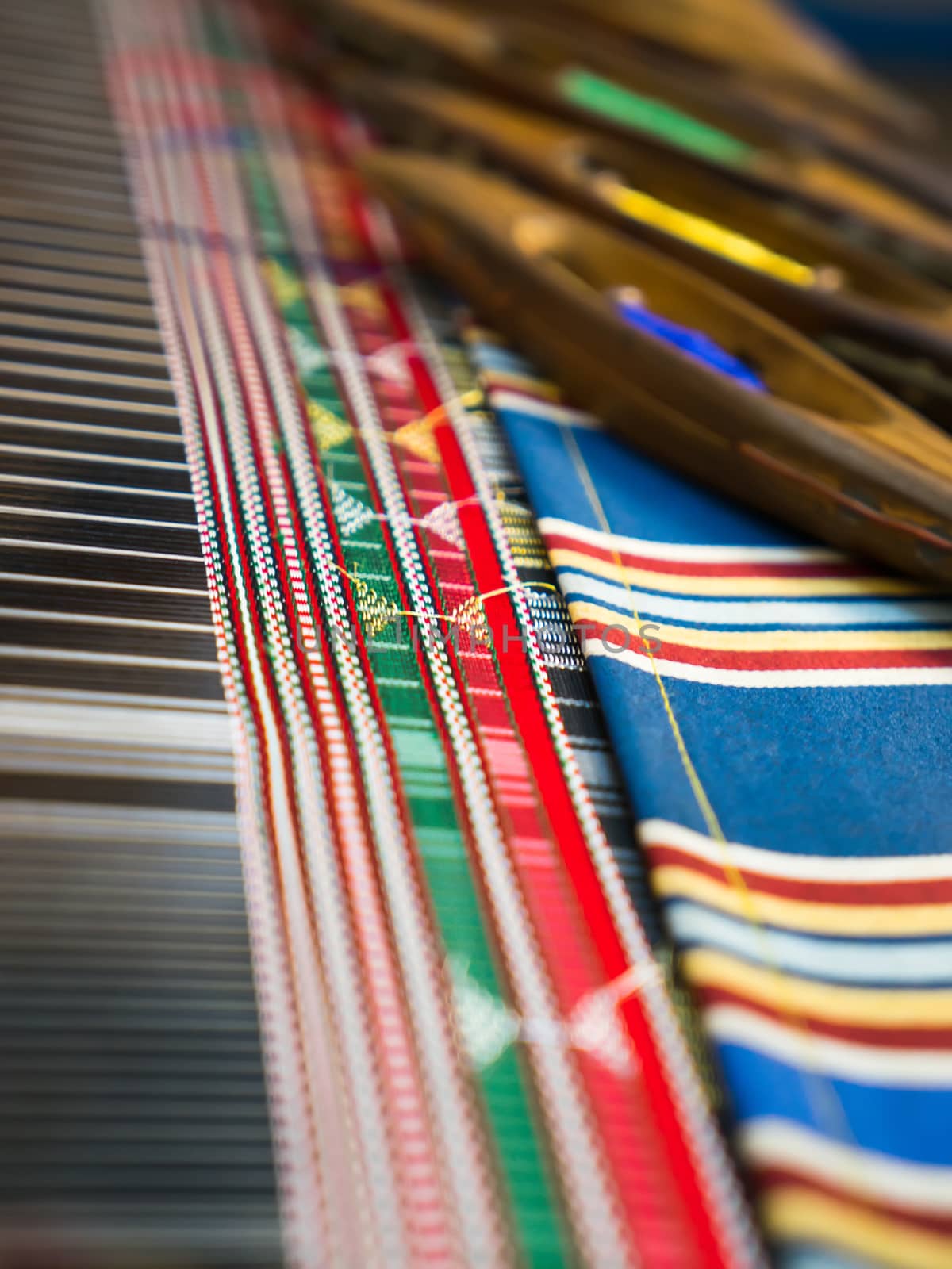 Weaving shuttles and colorful textile with pattern. Artistic shallow DOF