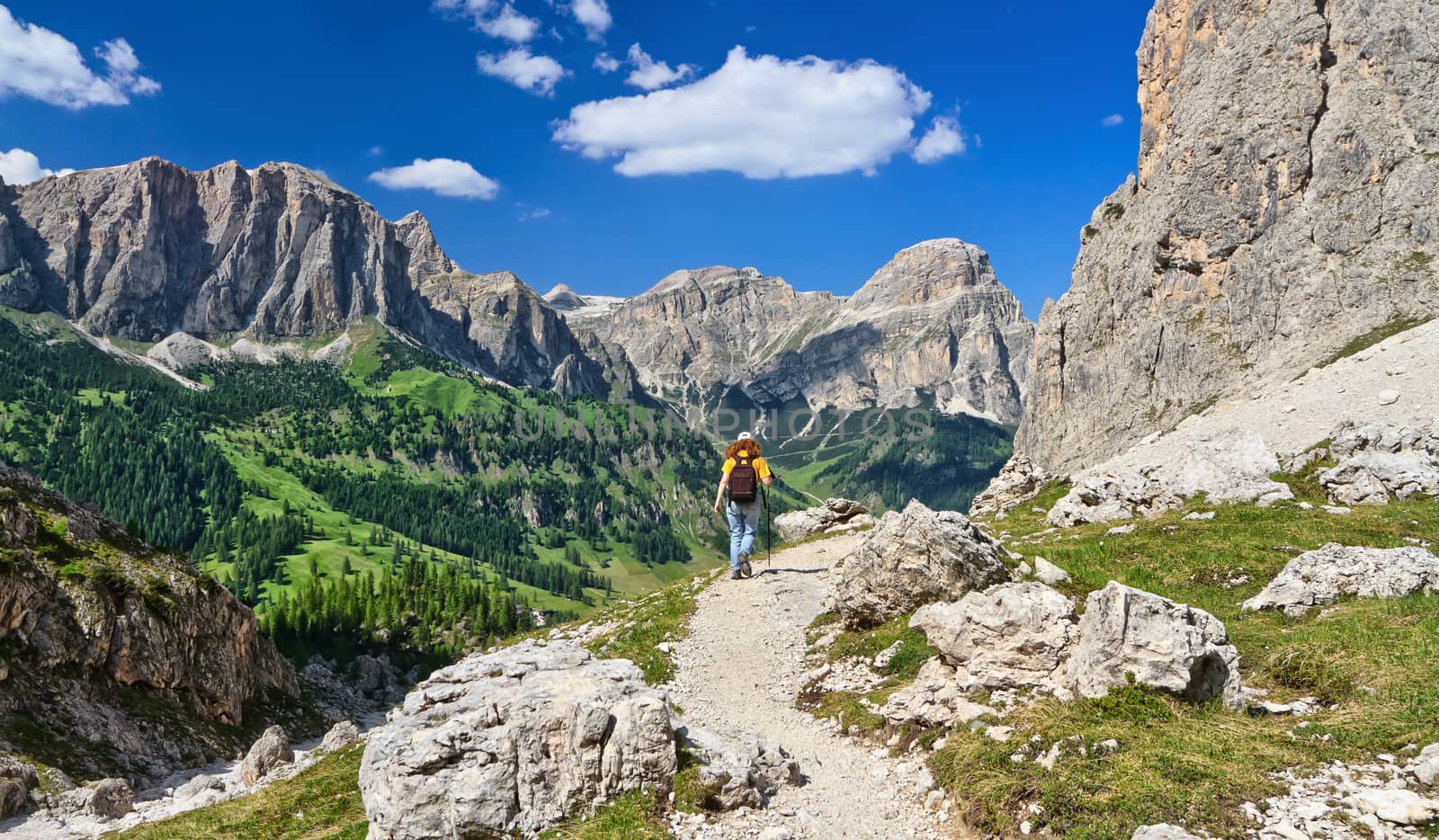 woman on footpath  in Sella mountain, on background Colfosco and Badia Valley, south Tyrol, Italy