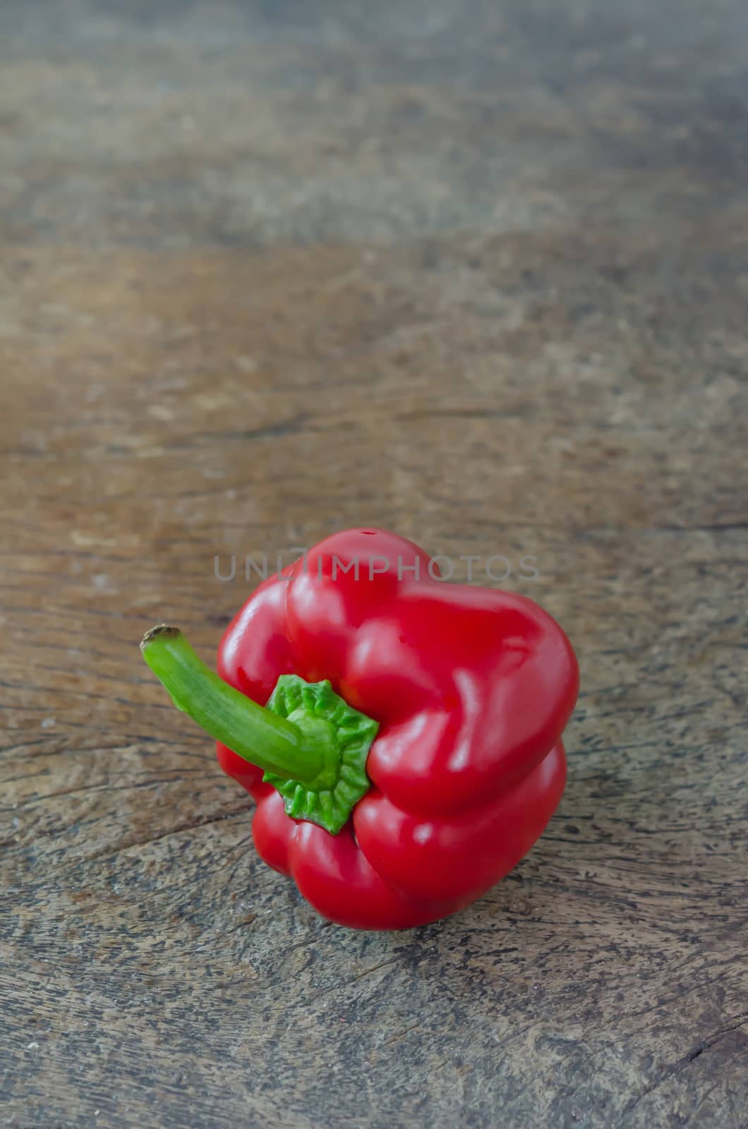 single red bell peppers on wooden table