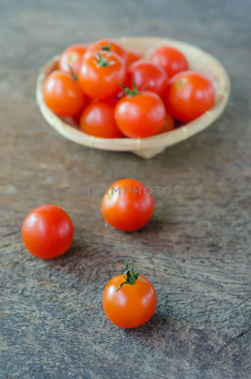 Red cherry tomatoes  on a textured  wooden background and basket