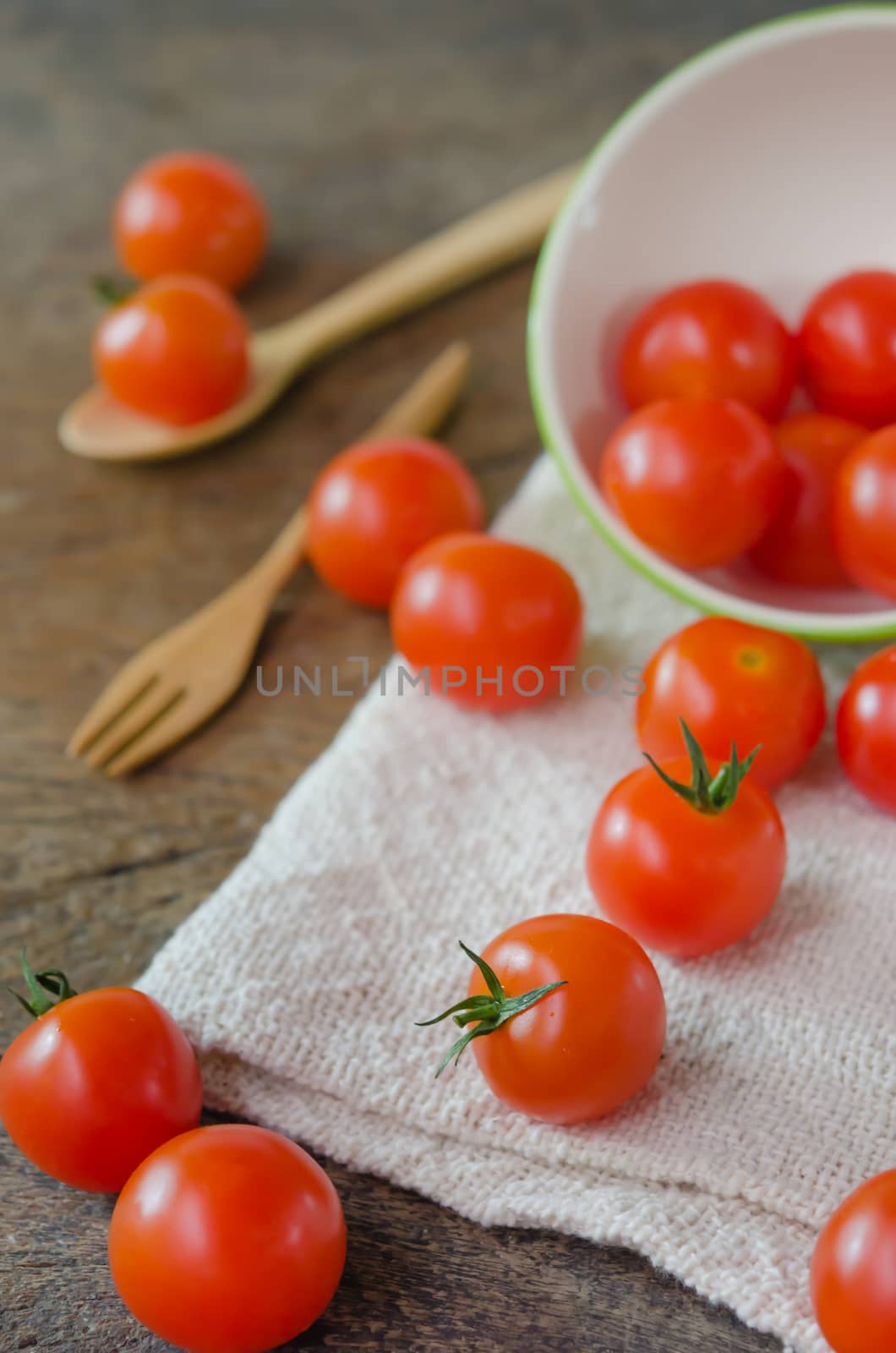 Red cherry tomatoes  spilling out from green bowl