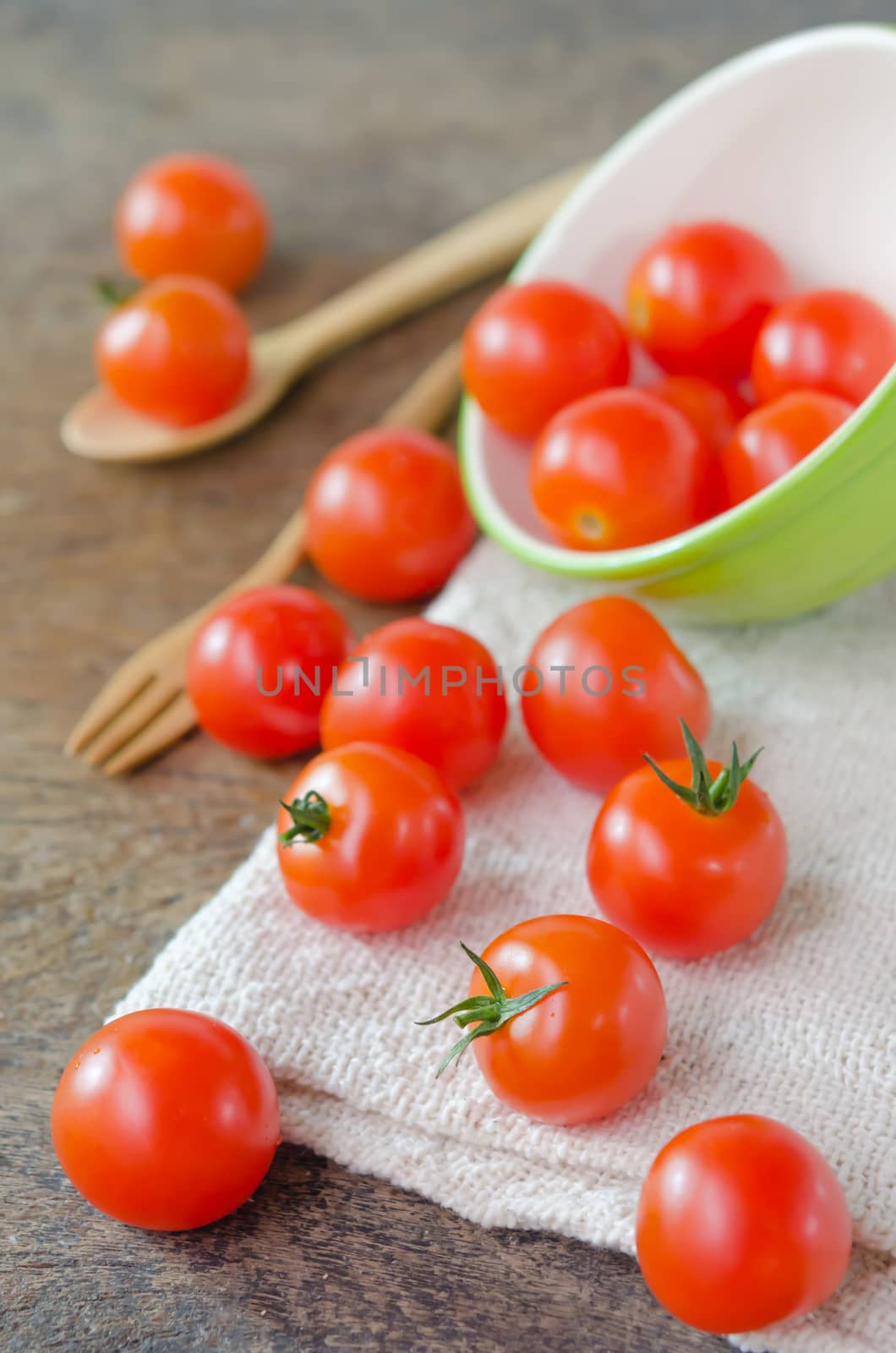 Red cherry tomatoes  spilling out from bowl with spoon and fork
