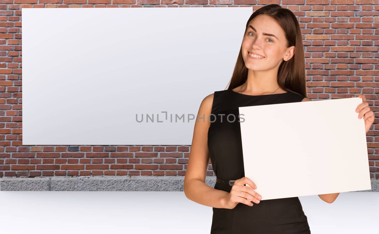 Businesswoman holding paper sheet. Brick wall and white placard as backdrop