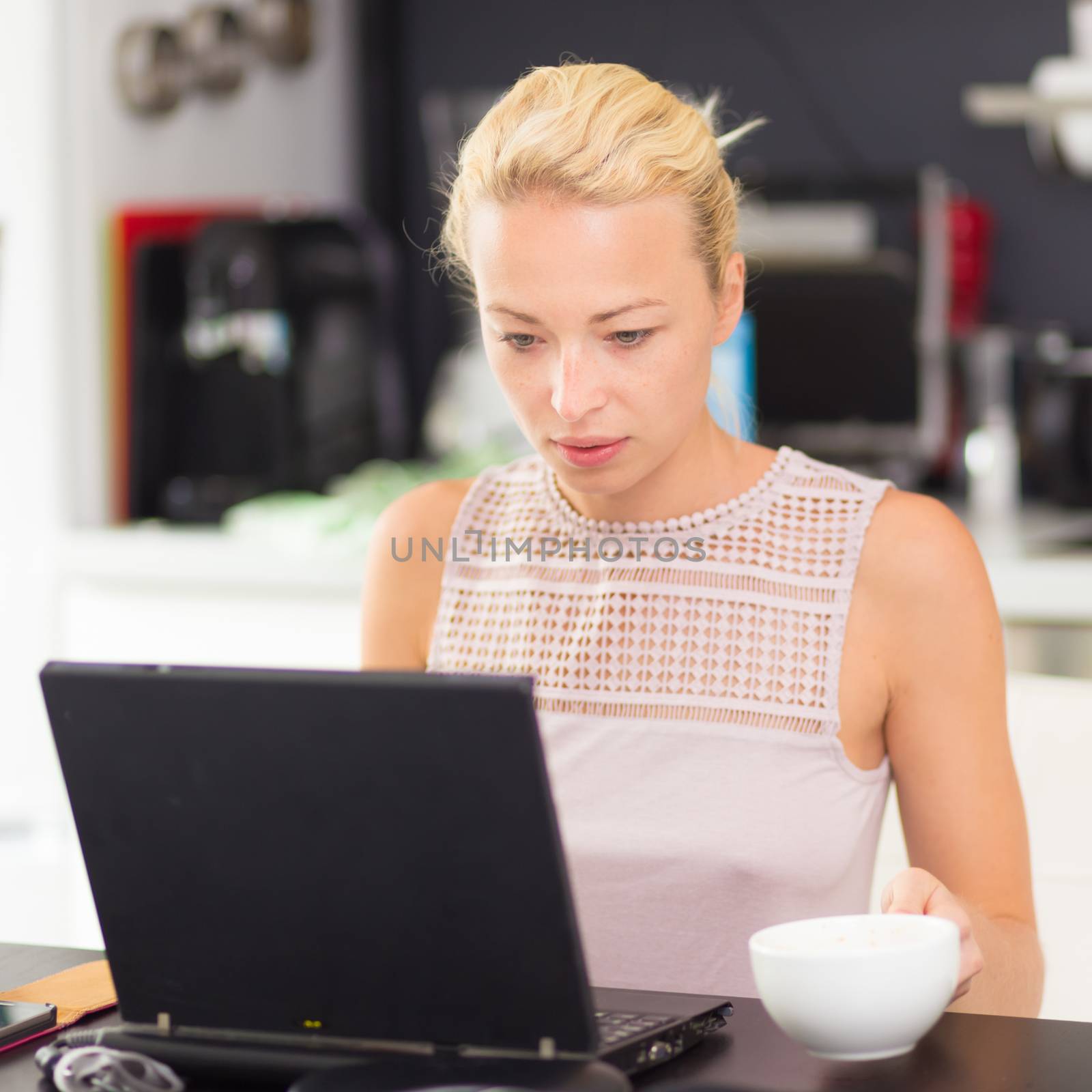 Business woman working remotly from her dining table. Home kitchen in the background.