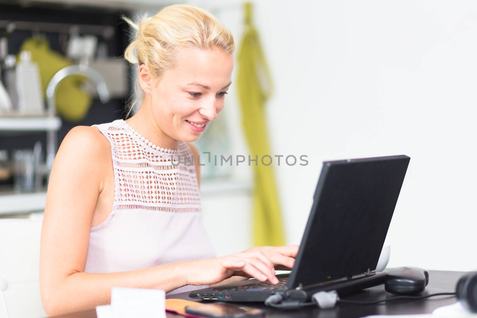Business woman working remotly from her dining table. Home kitchen in the background.