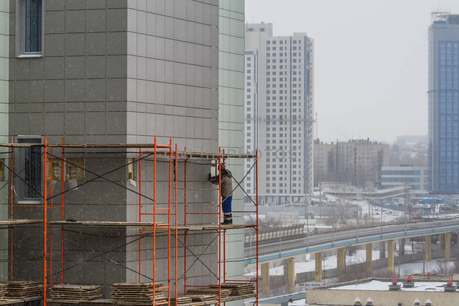 A construction worker on a high wall - Stock Image