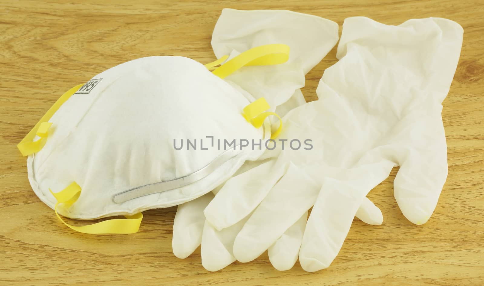 N95 white mask and gloves for disease prevention, placed on wooden floor.                                