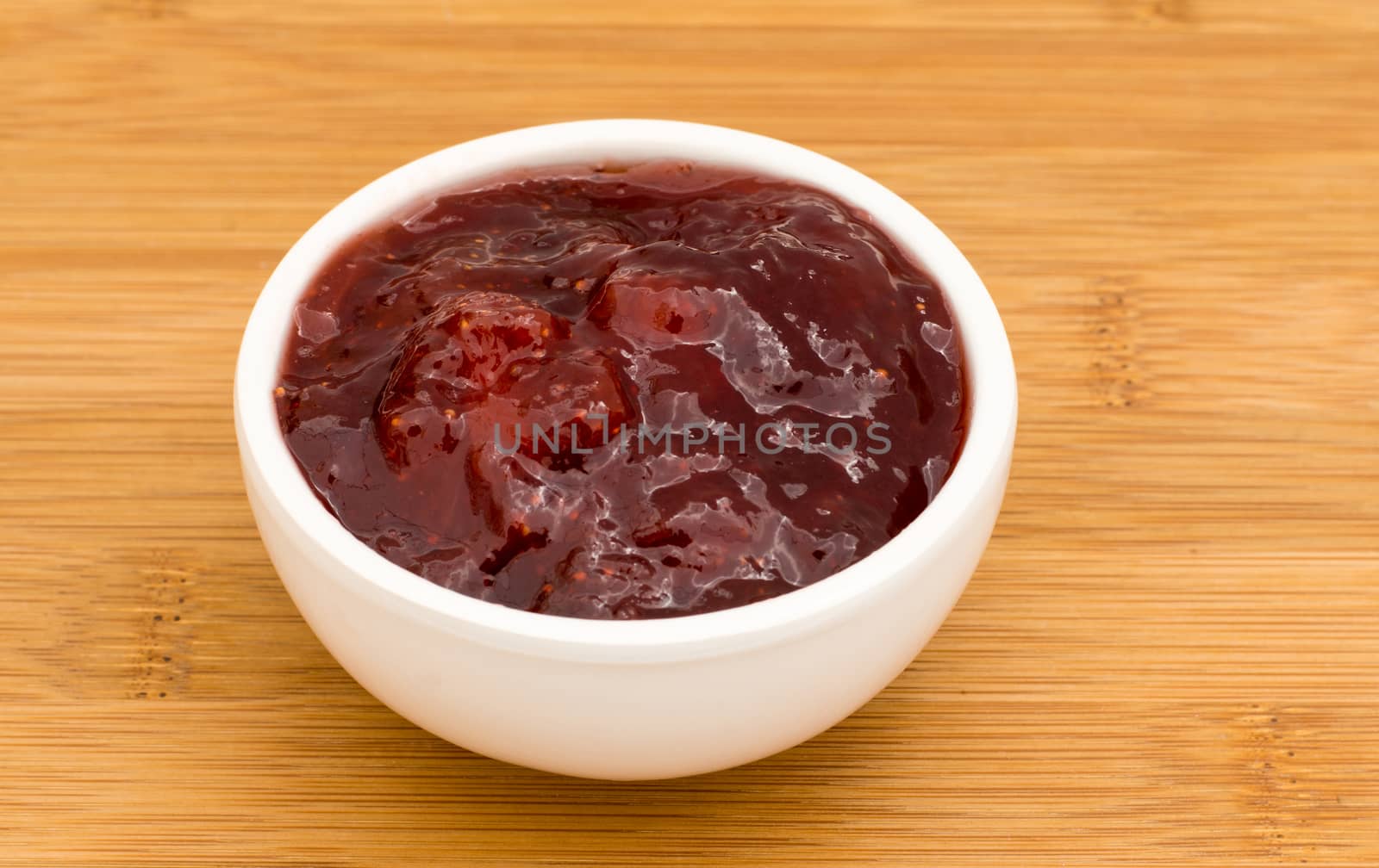 Small pot of strawberry Jam on a wooden board 