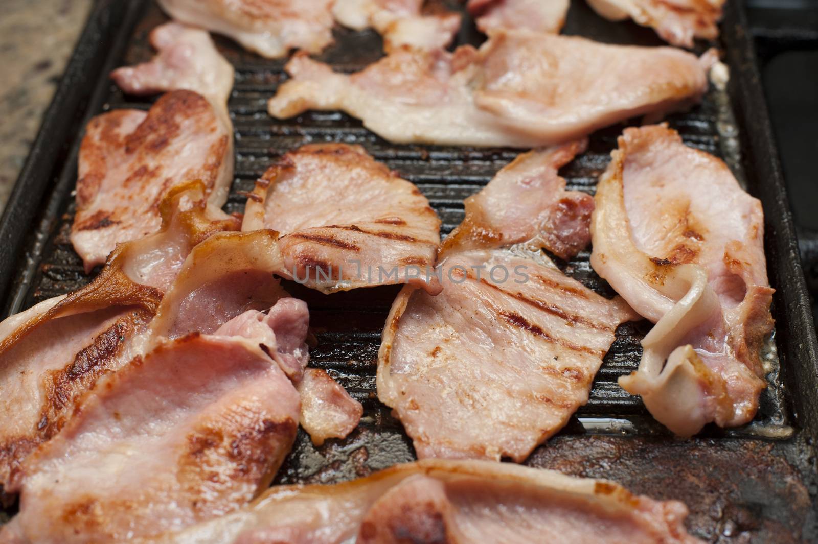 Rashers of smoked bacon on a griddle by stockarch