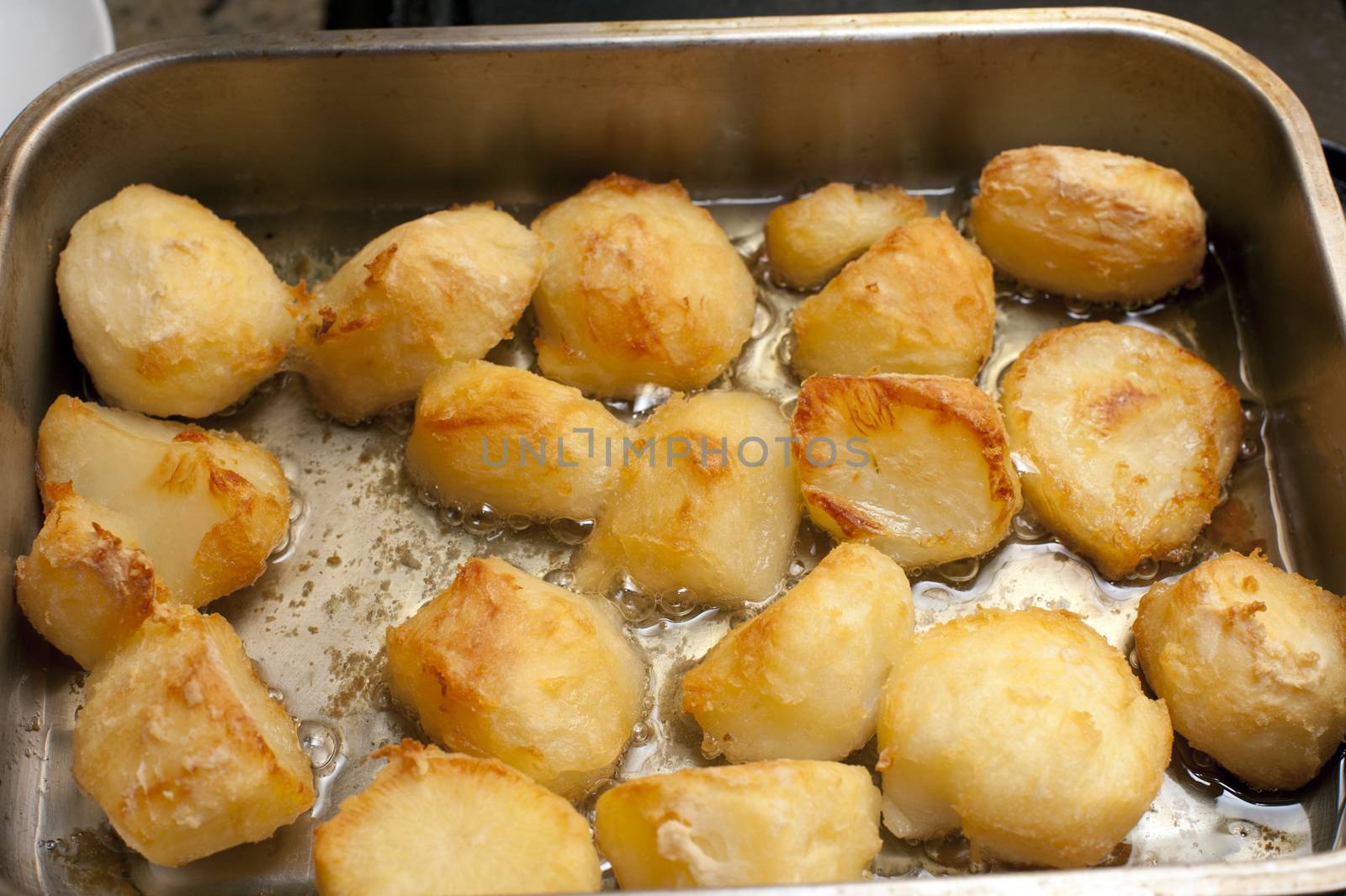 Delicious golden crispy roast potatoes in a baking tray fresh from the oven, high angle view