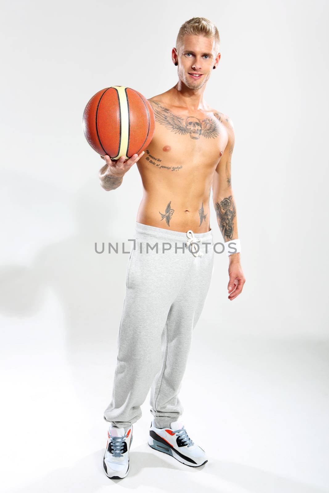 Attractive young boy with an orange ball for basketball, tattooed in