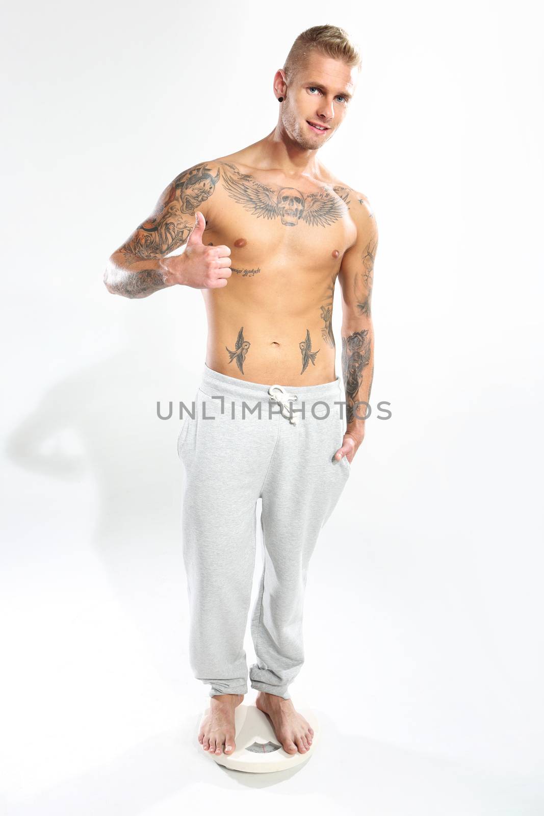 Attractive man standing on the scales on a white background