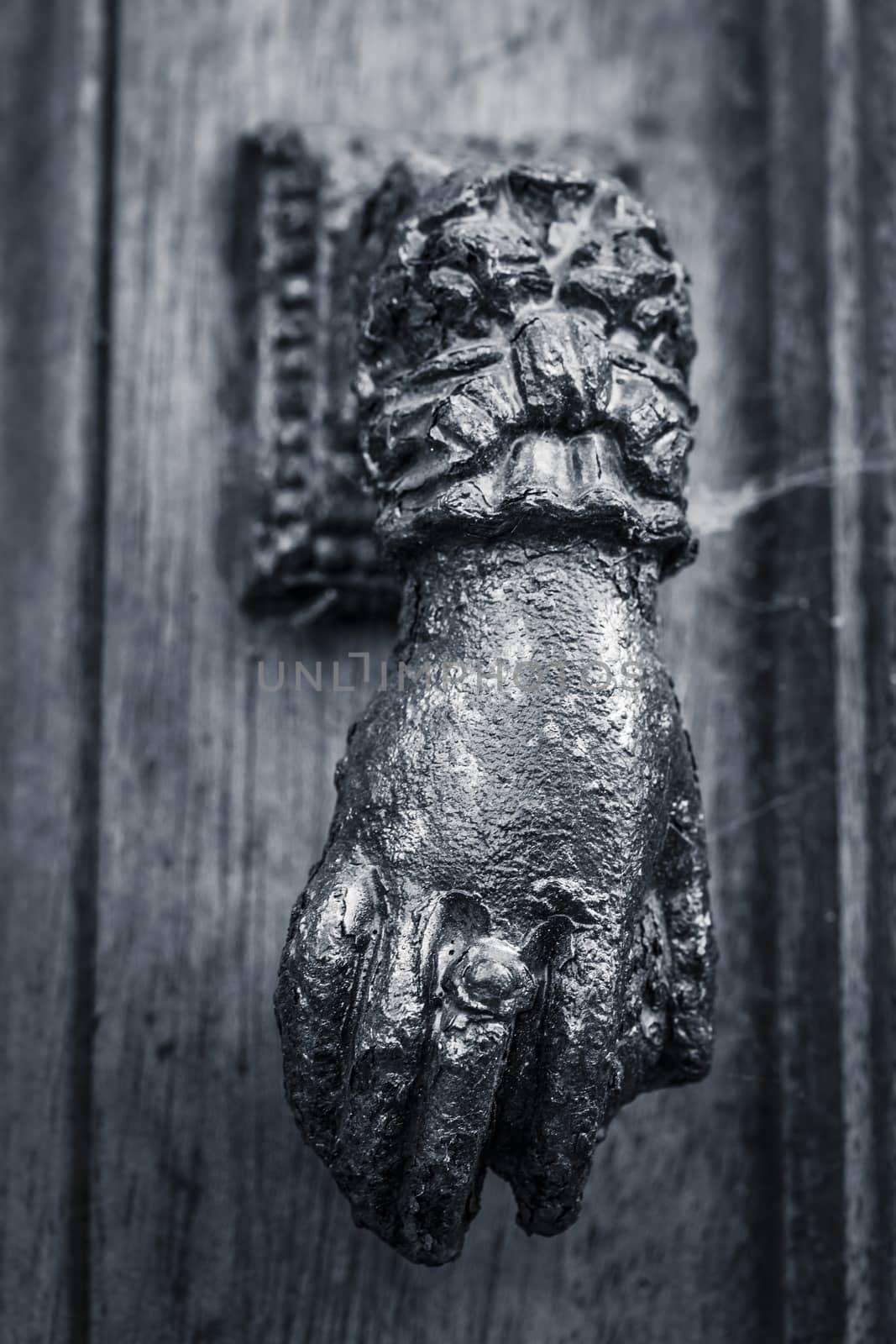 Close up picture of a hand shaped door knocker, black and white.