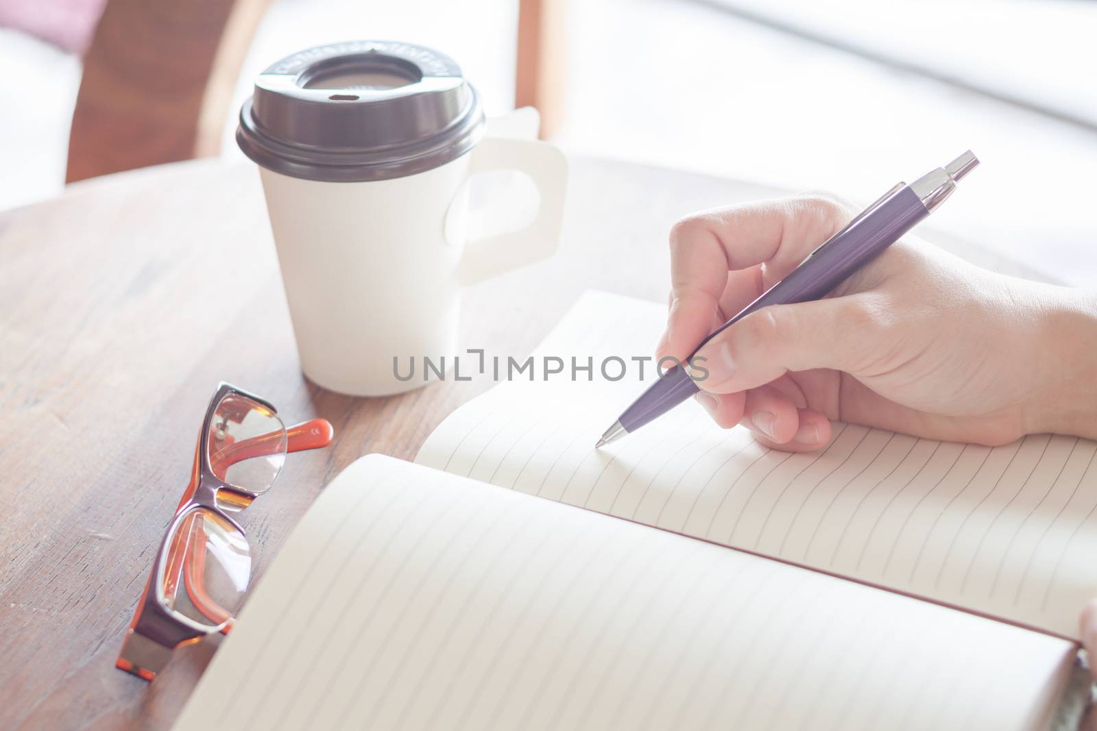 Woman writing on notebook, stock photo