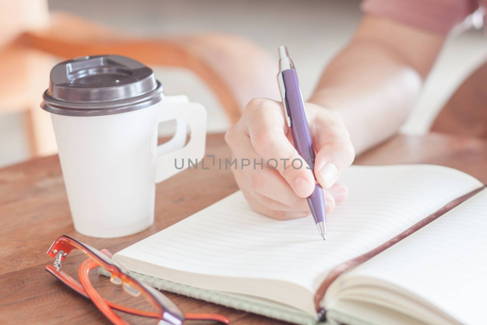 Woman writing on notepaper by punsayaporn