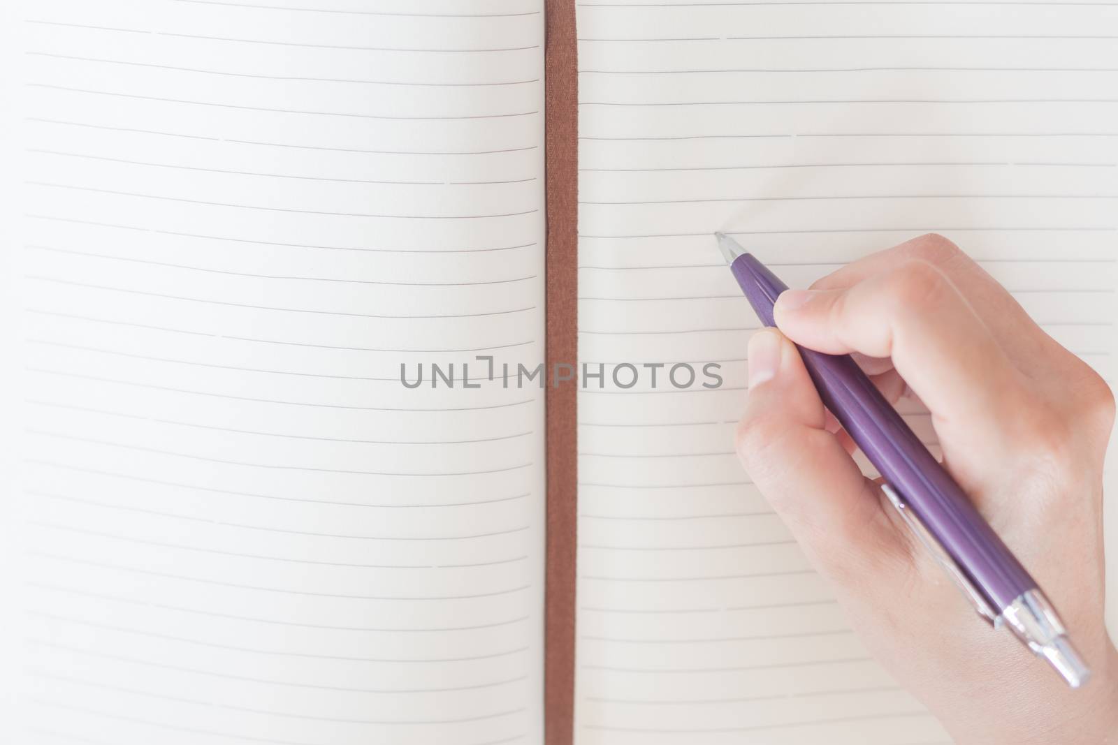 Closeup woman's hand writing on notebook by punsayaporn