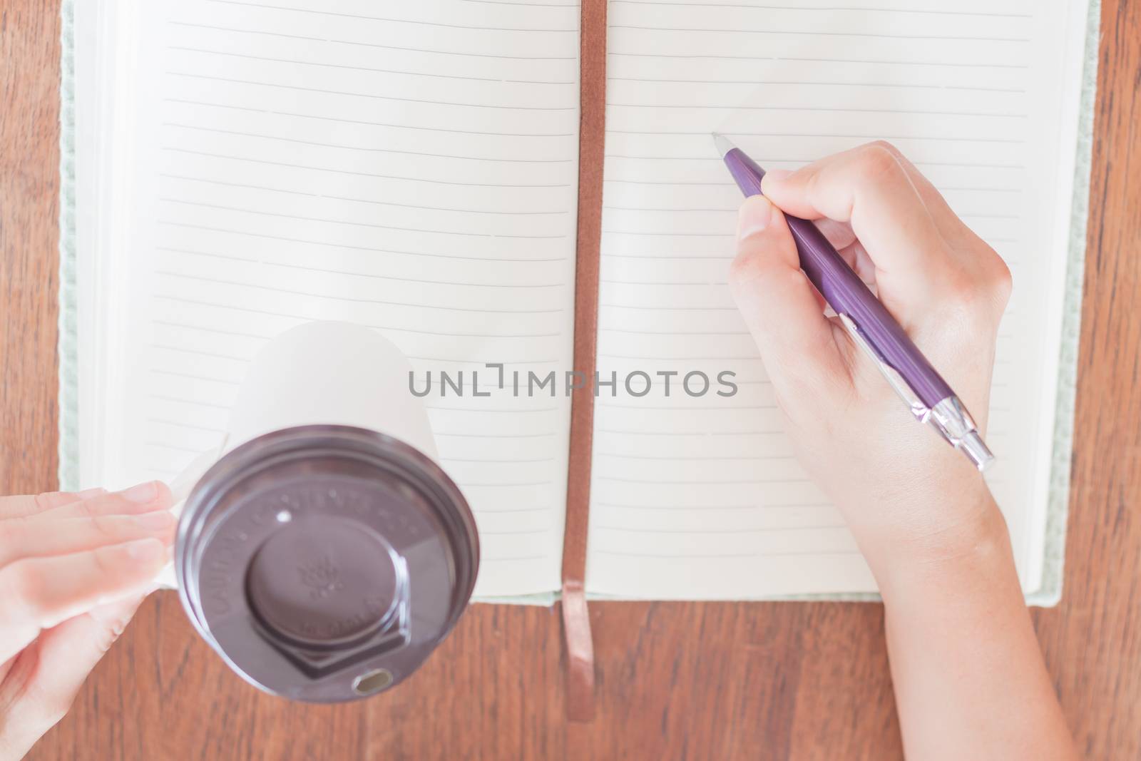 Woman's hand writing on notebook by punsayaporn