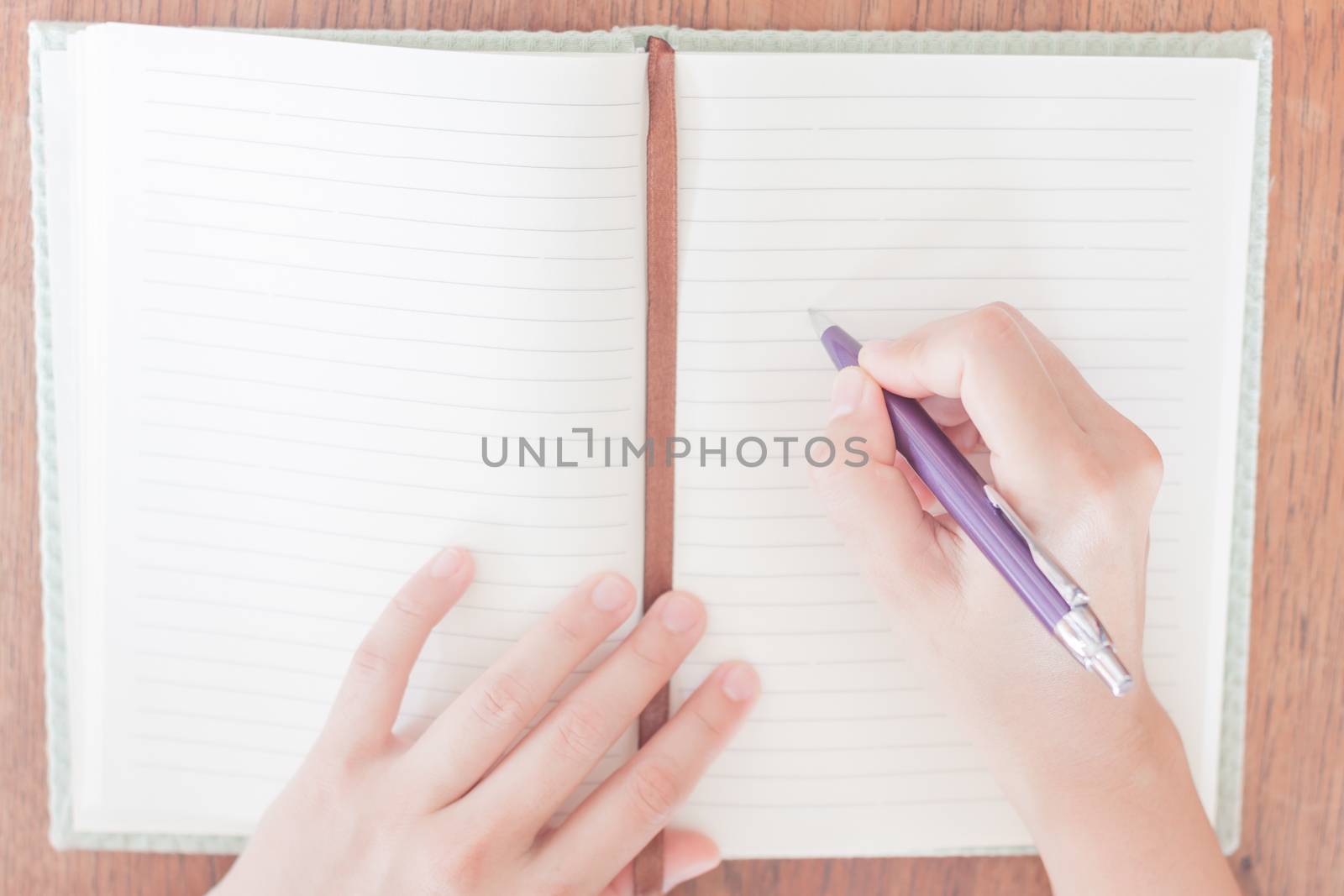 Woman writing on her notebook, stock photo