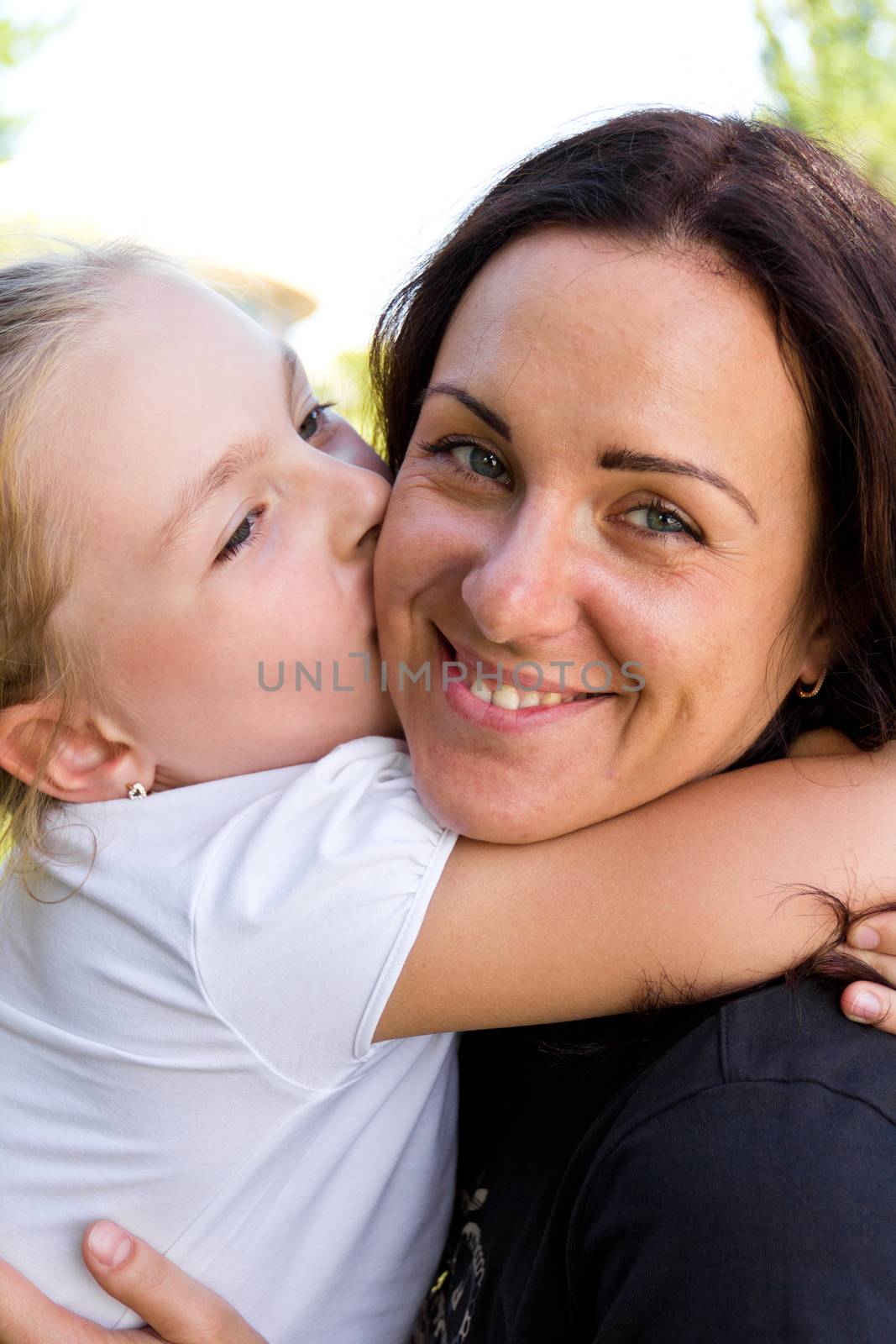 Photo of kissing mother and daughter in summer