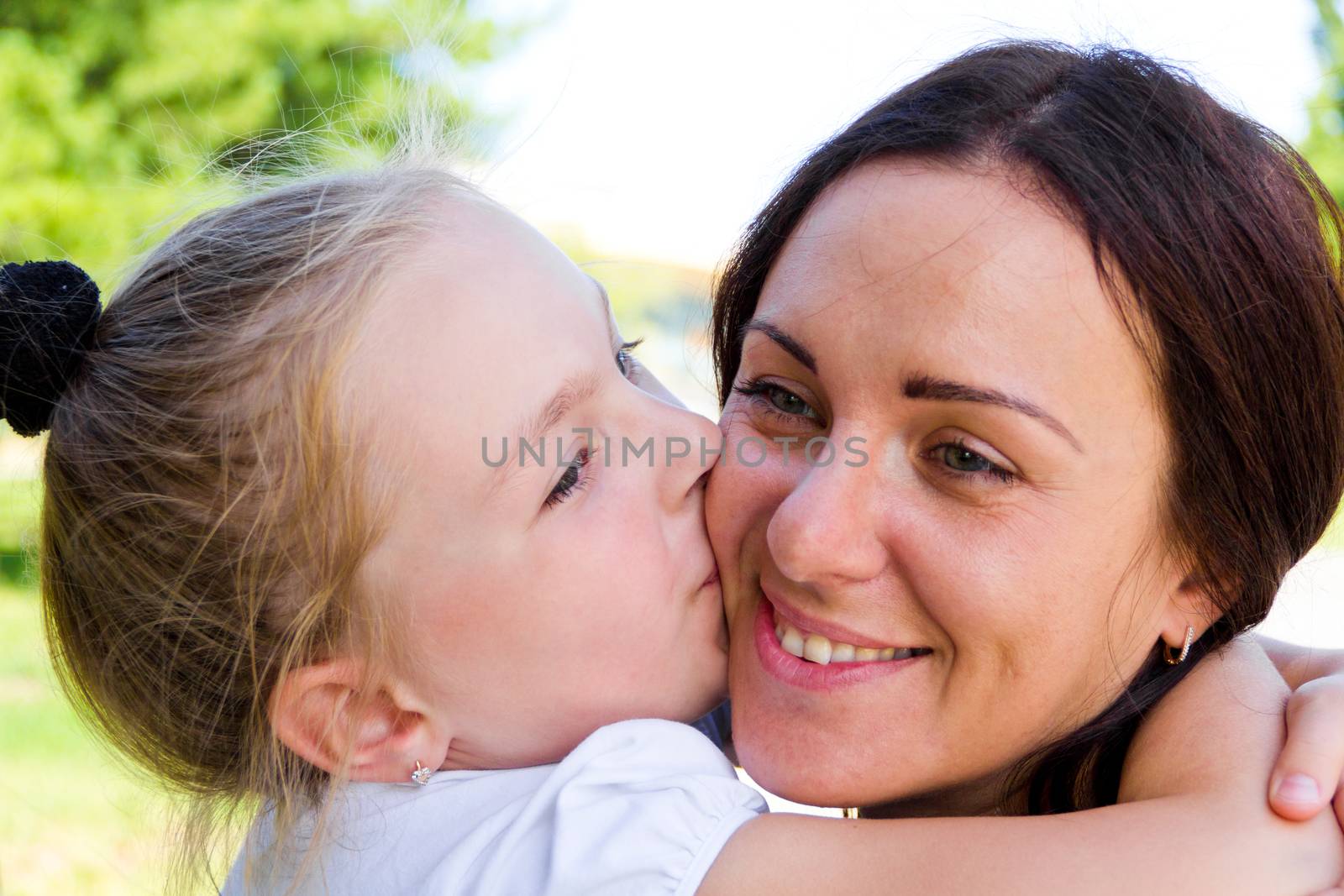 Photo of kissing mother and daughter in summer