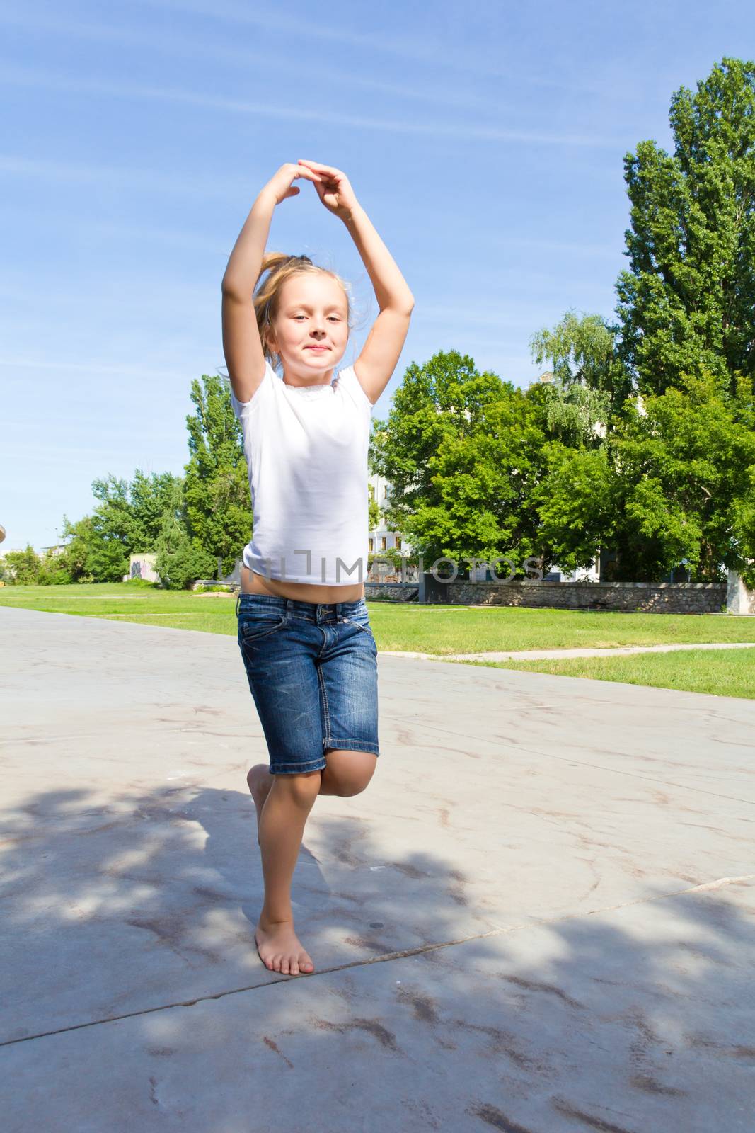 Cute girl with blond hair jumping on one leg