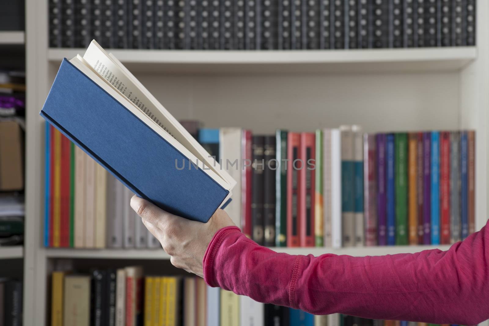 blue book in pink woman arm over library background