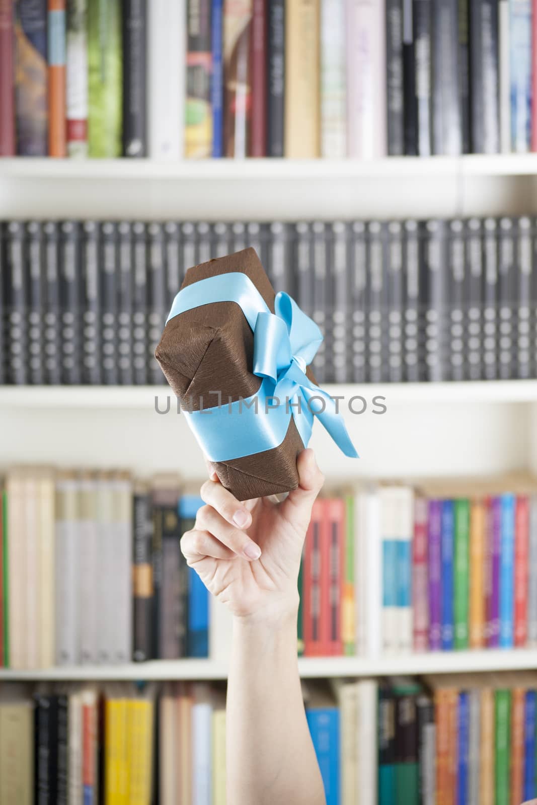 gift box in woman hands over library background