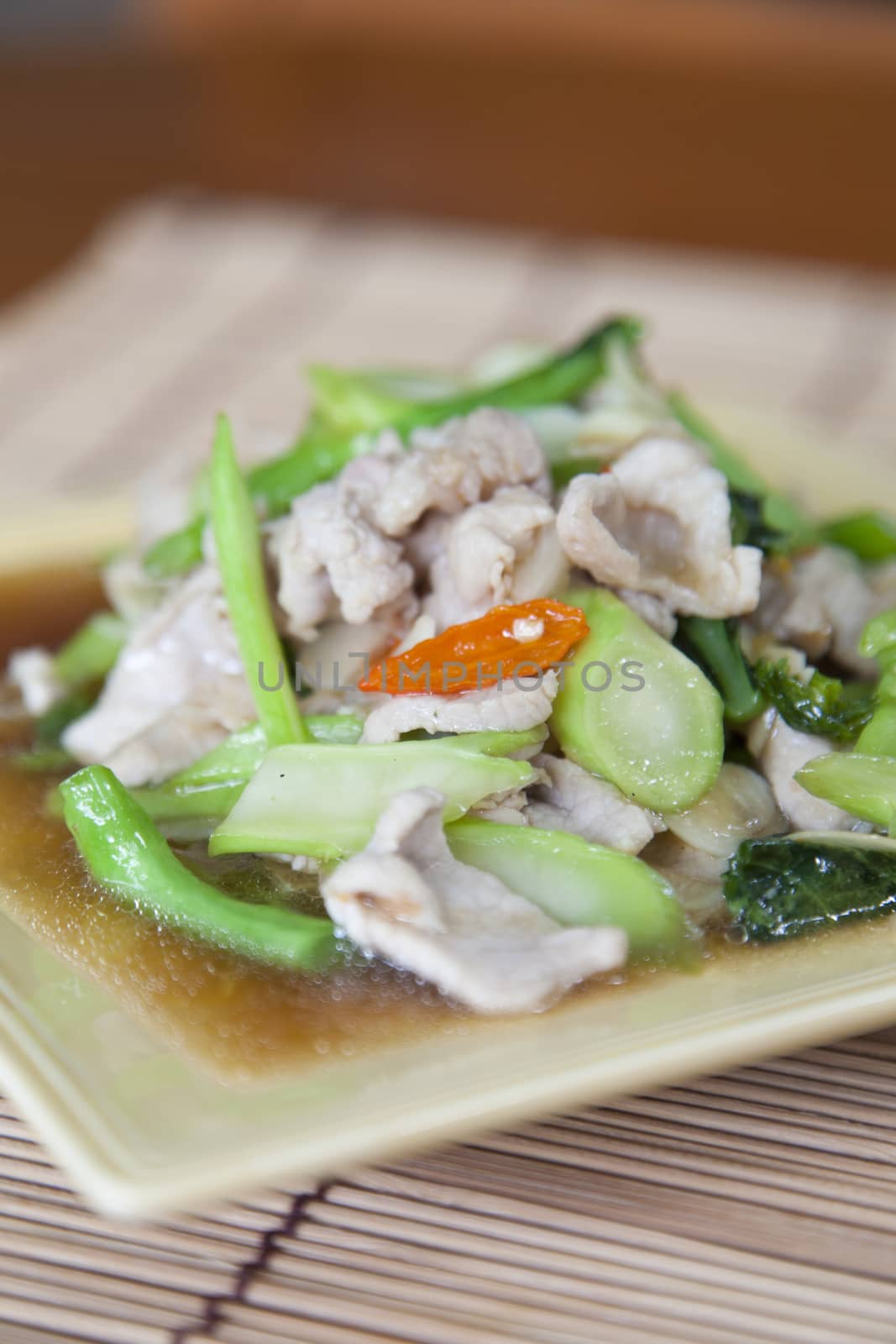 Fried pork with vegetable oil Rectangular plate placed on a wooden plate.