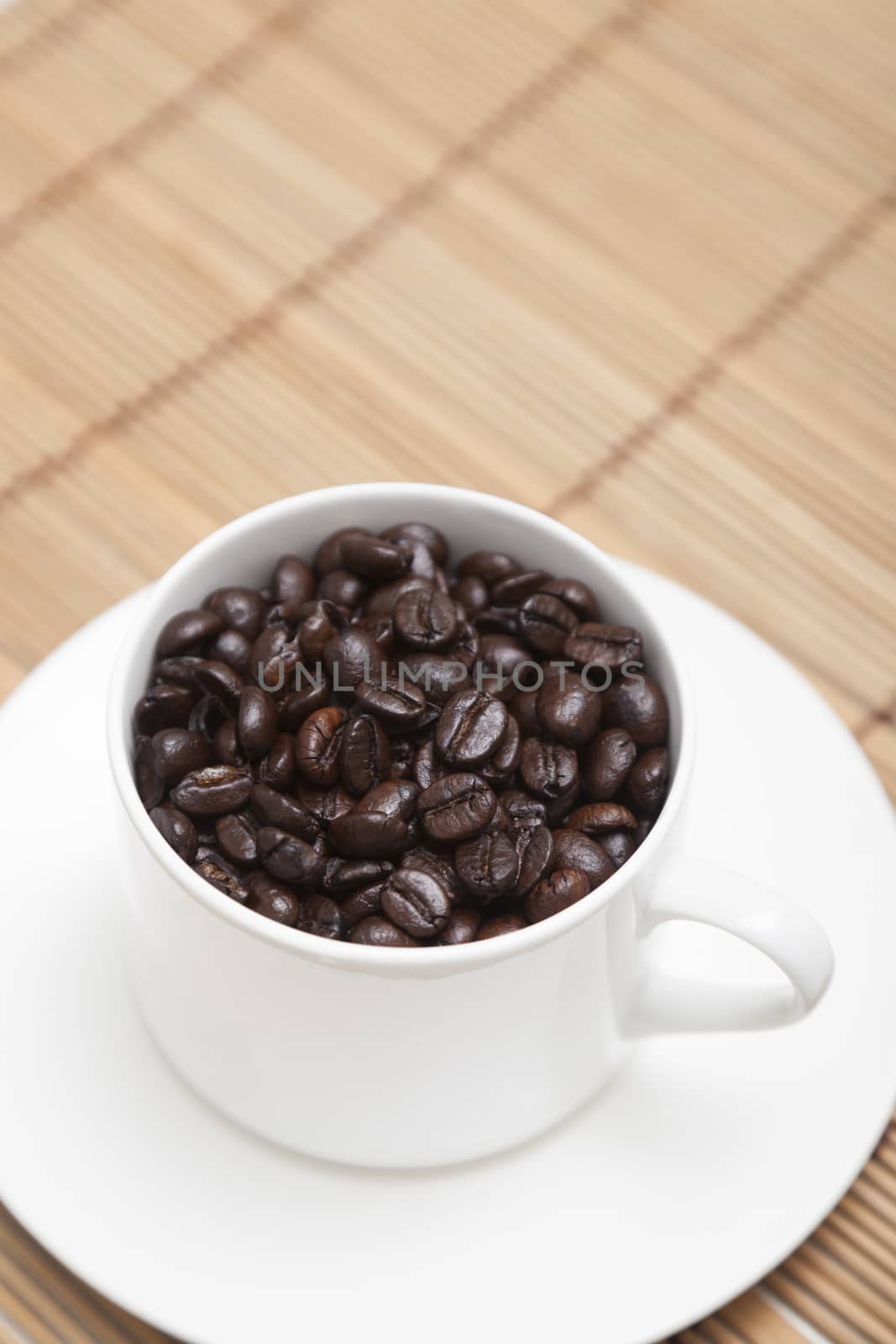 Roasted coffee beans In white coffee cup on wood.