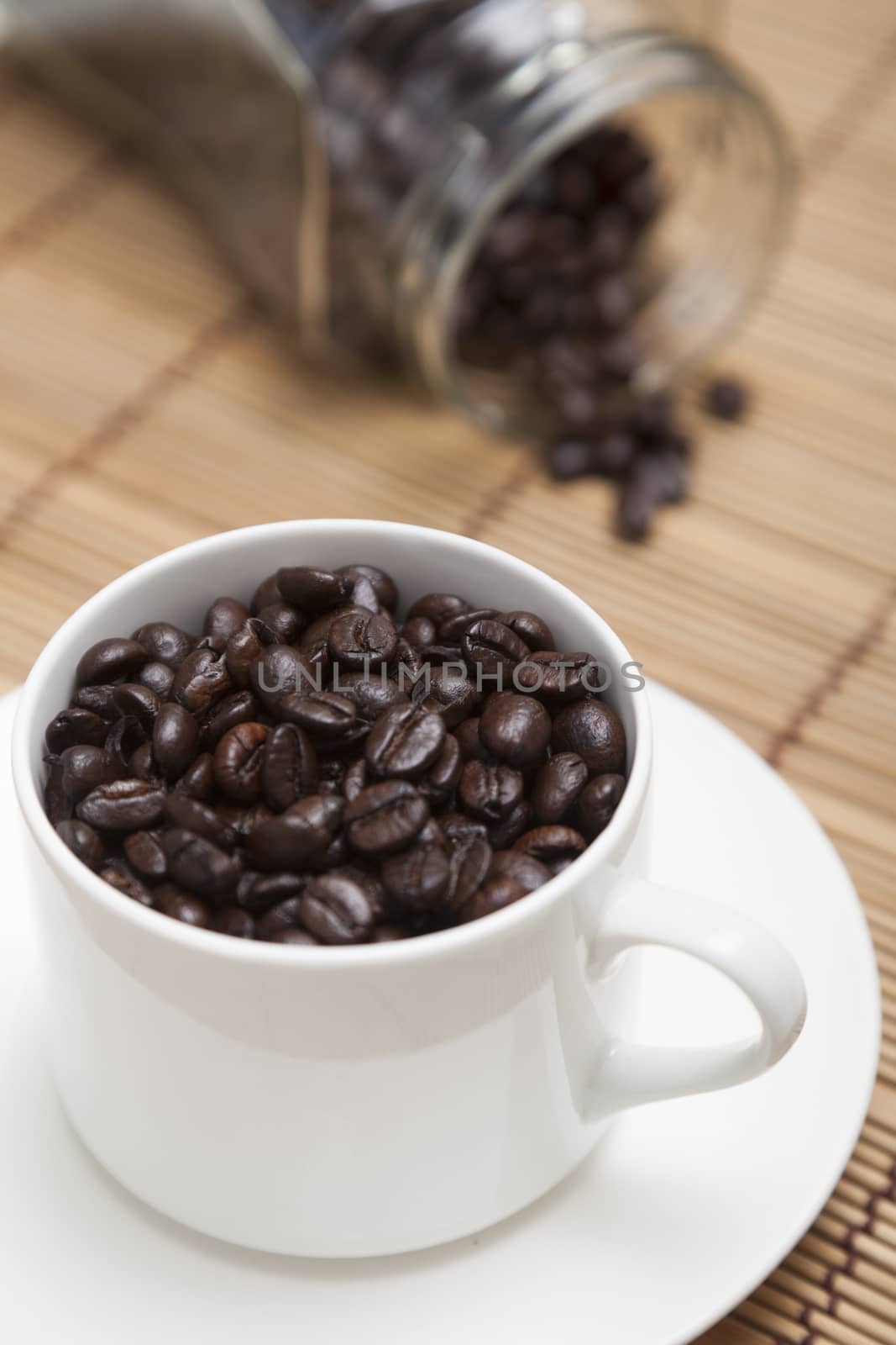 Roasted coffee beans in glass and bottle. Placed on a wooden table top.