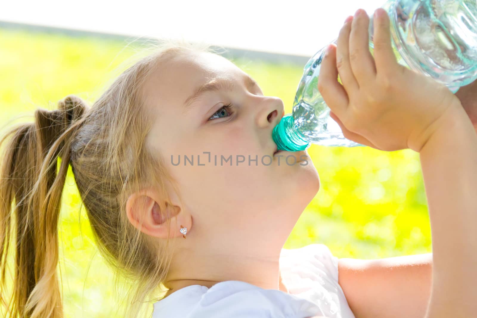 Cute girl with blond long hair drinking water
