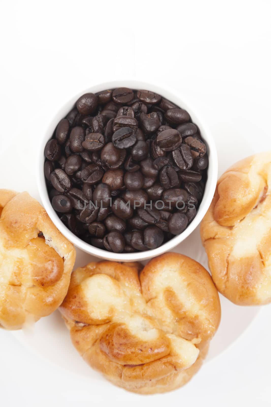 Roasted coffee beans in a glass Bread on plate On a white background