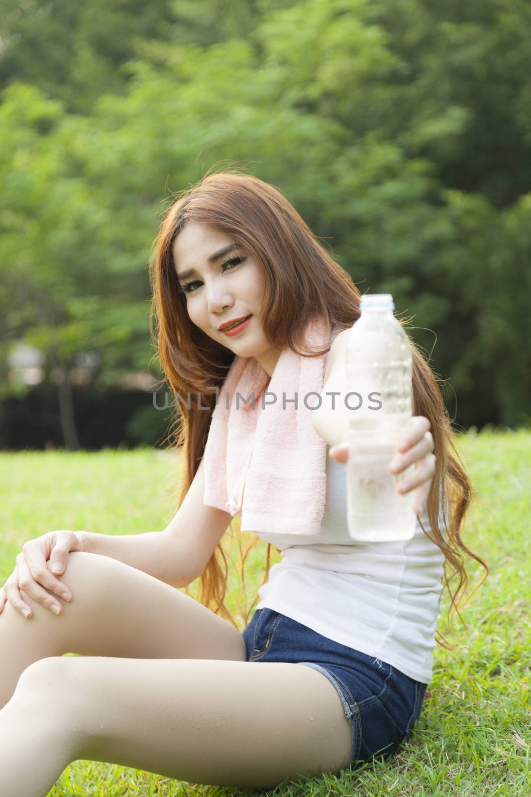 Woman pouring water from it. Sitting On the lawn in the park.