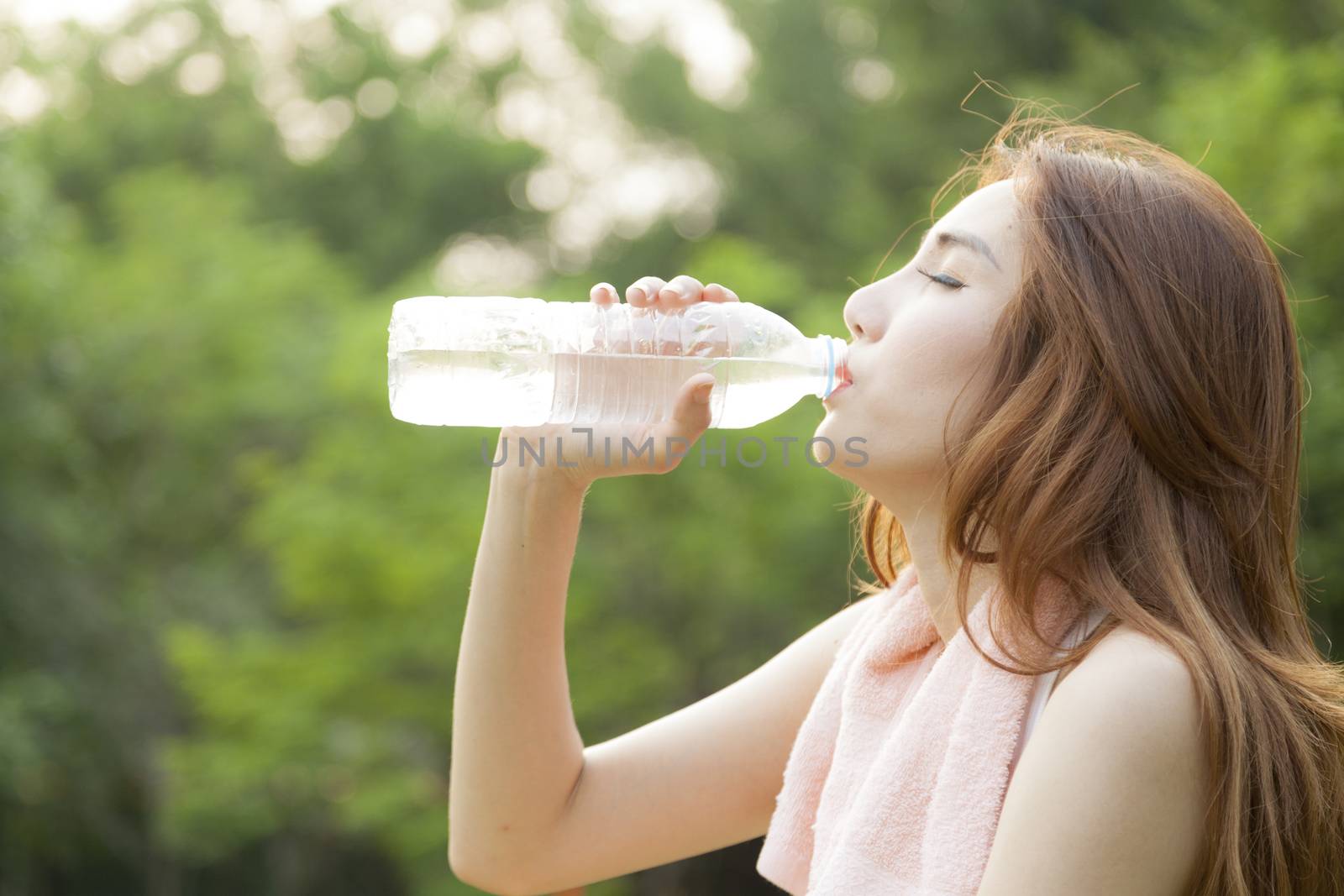 Woman sit and drink after exercise. On the lawn after a workout in the park.