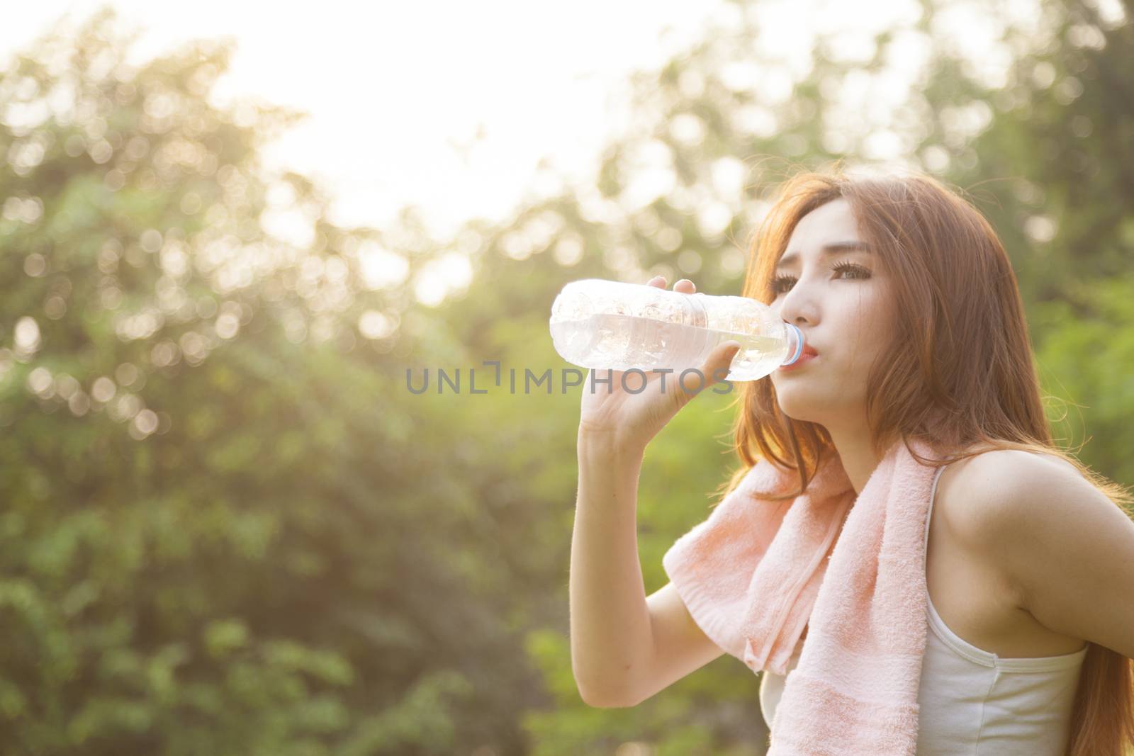 Woman sit and drink after exercise. On the lawn after a workout in the park.
