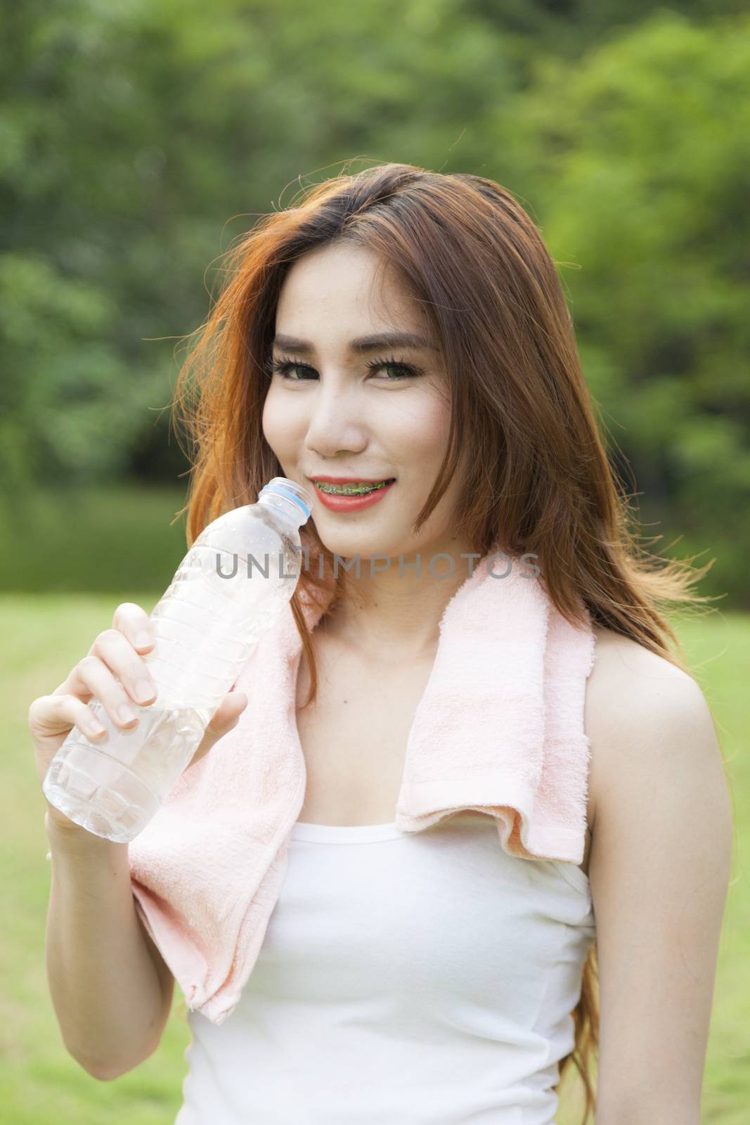 Woman standing water breaks during exercise. Jogging in the park during the evening.