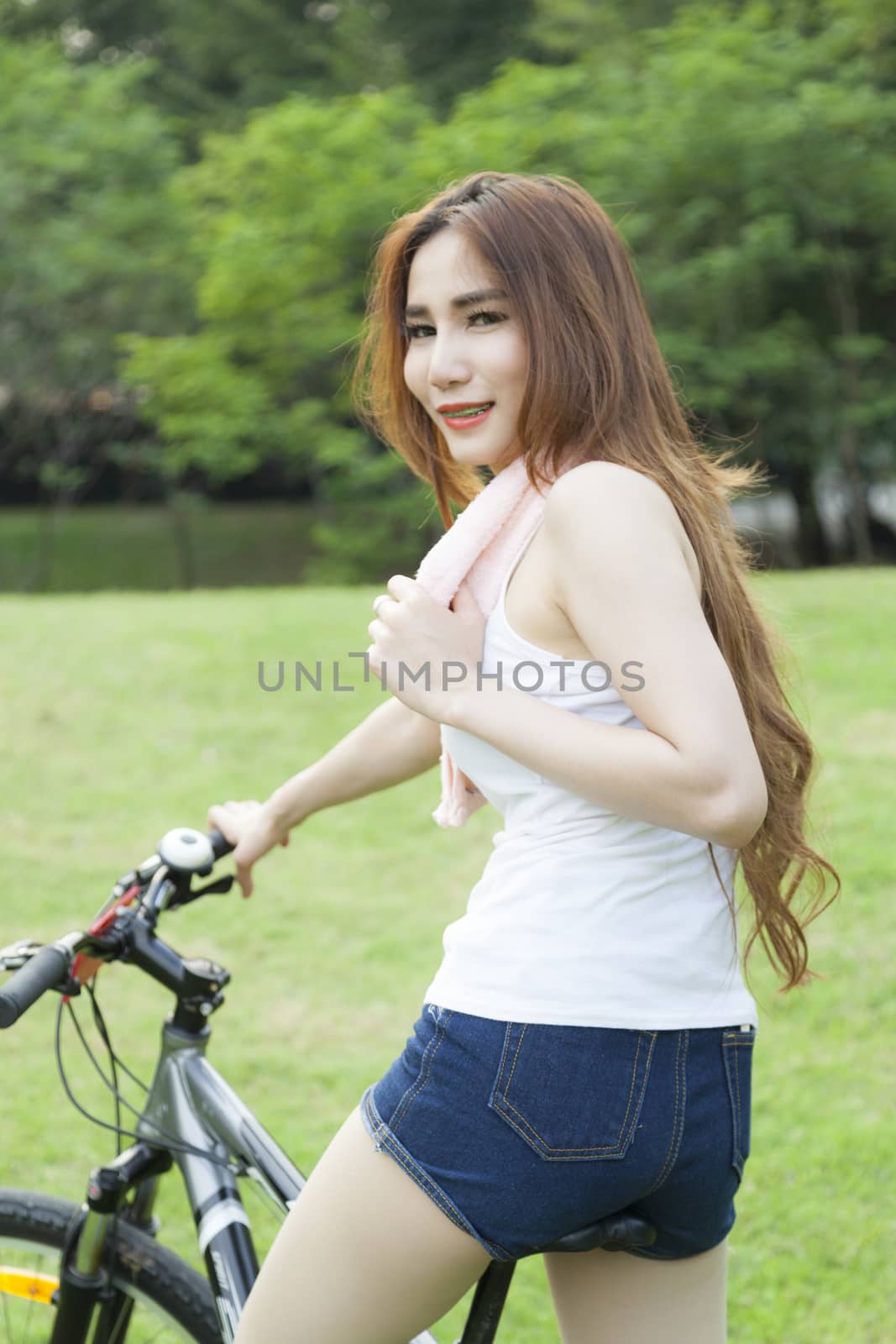 Woman riding an exercise bike in the park. On the lawn in the evening.