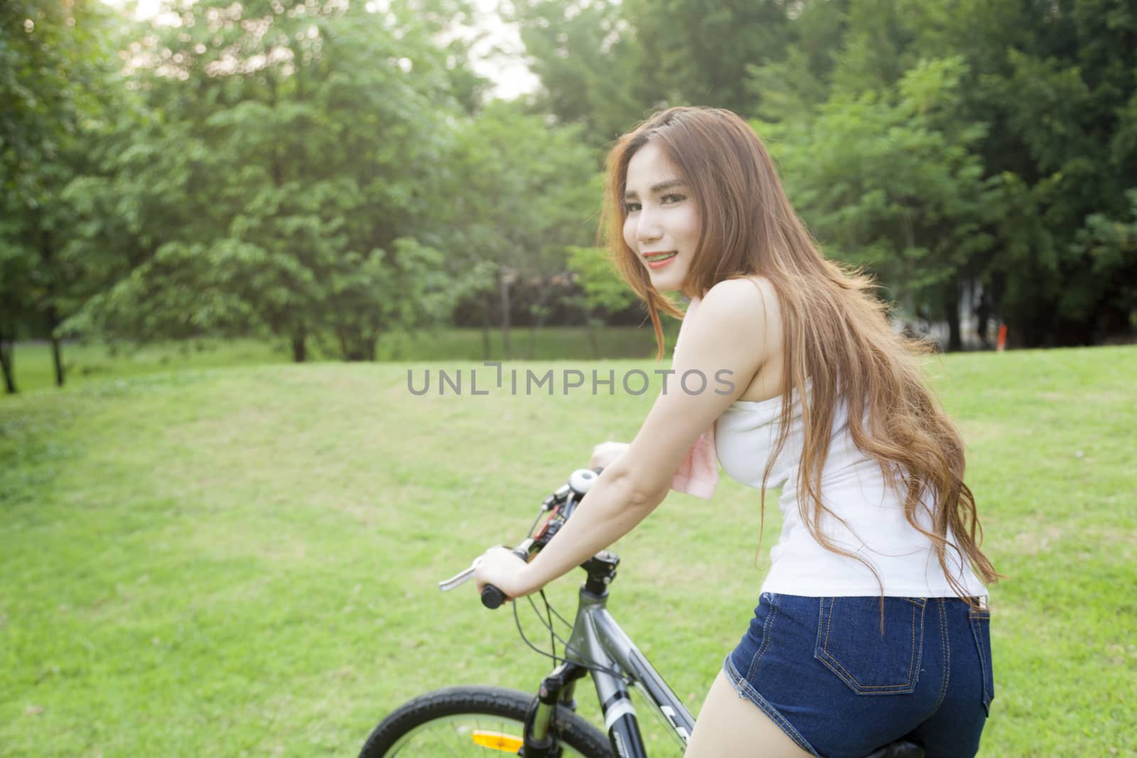 Woman riding an exercise bike in the park. On the lawn in the evening.