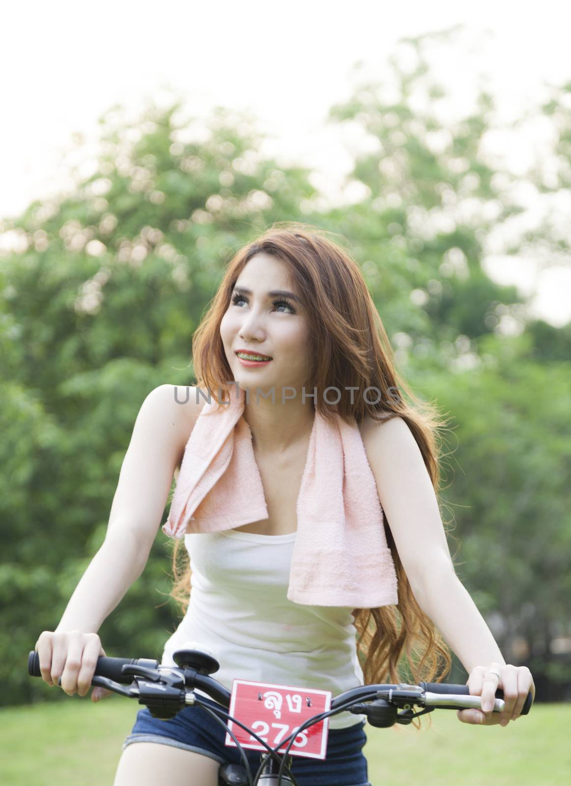 Woman riding an exercise bike in the park. On the lawn in the evening.