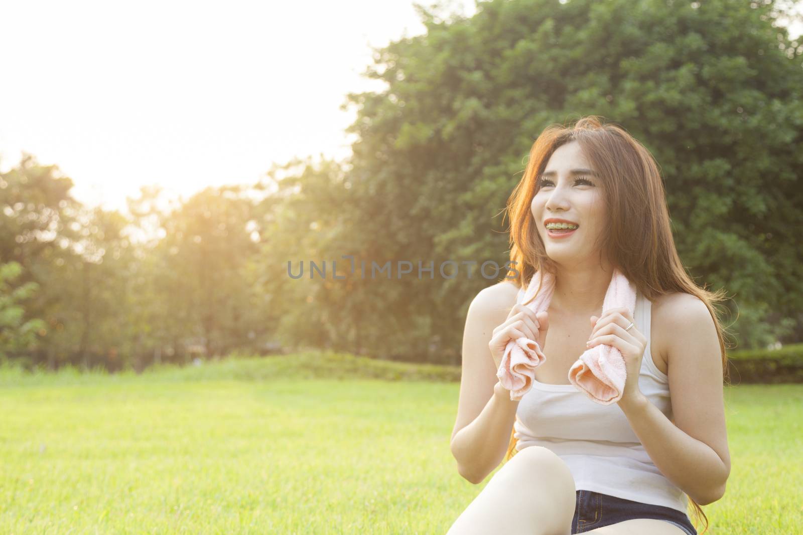 Woman Sitting after jogging. on grass in the park. In the evening