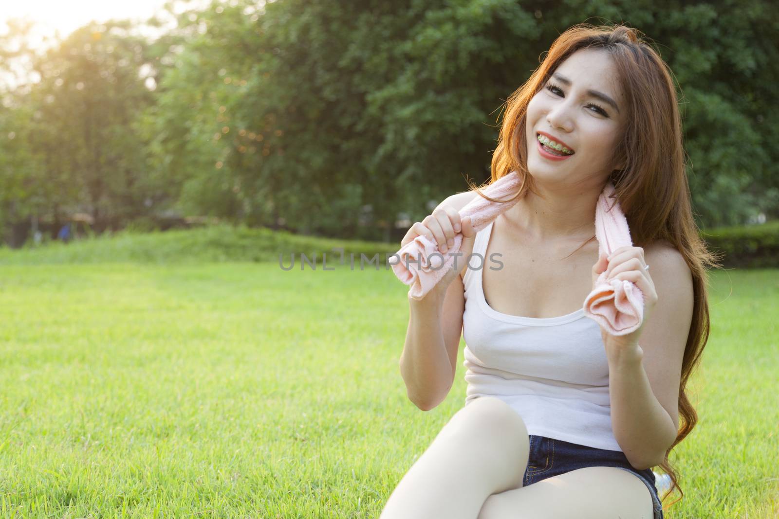 Woman Sitting after jogging. on grass in the park. In the evening