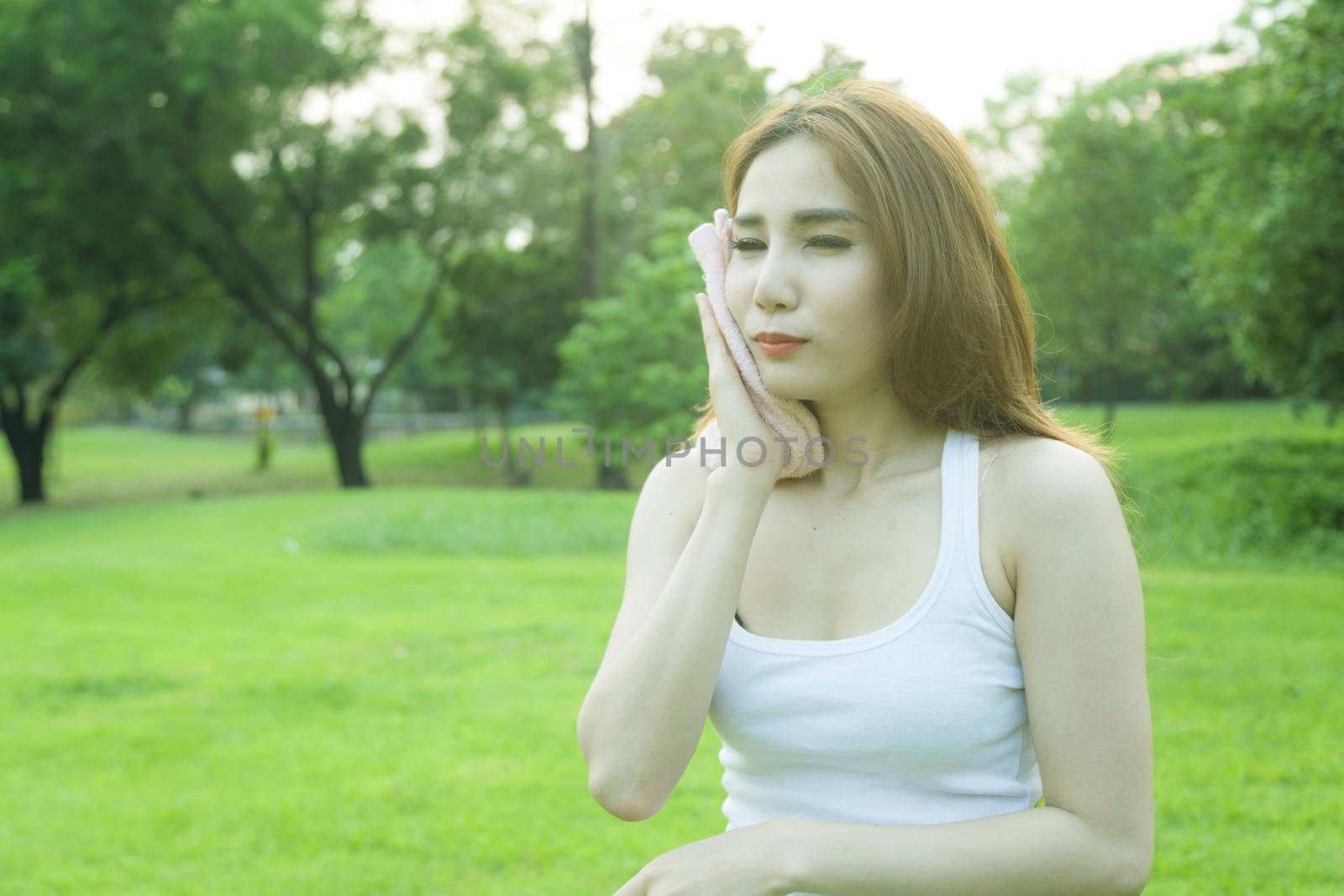 Woman standing rest after jogging. On lawn in the park