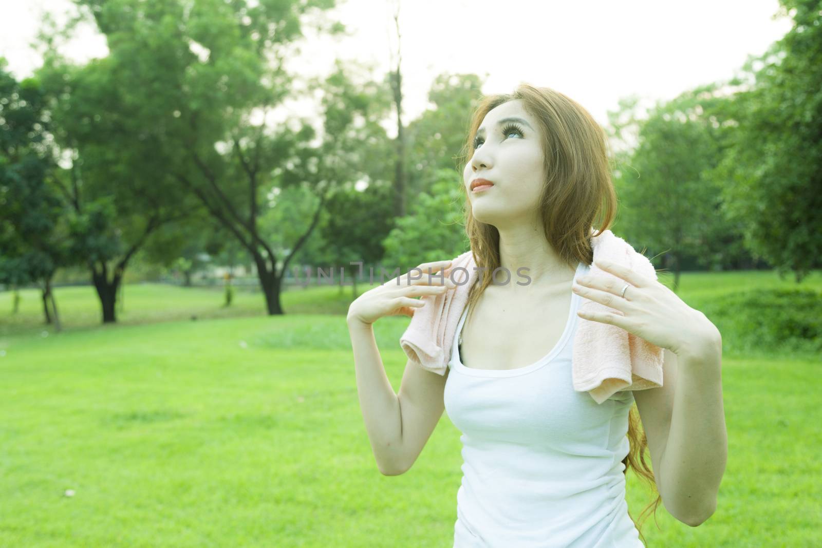 Woman standing rest after jogging. On lawn in the park