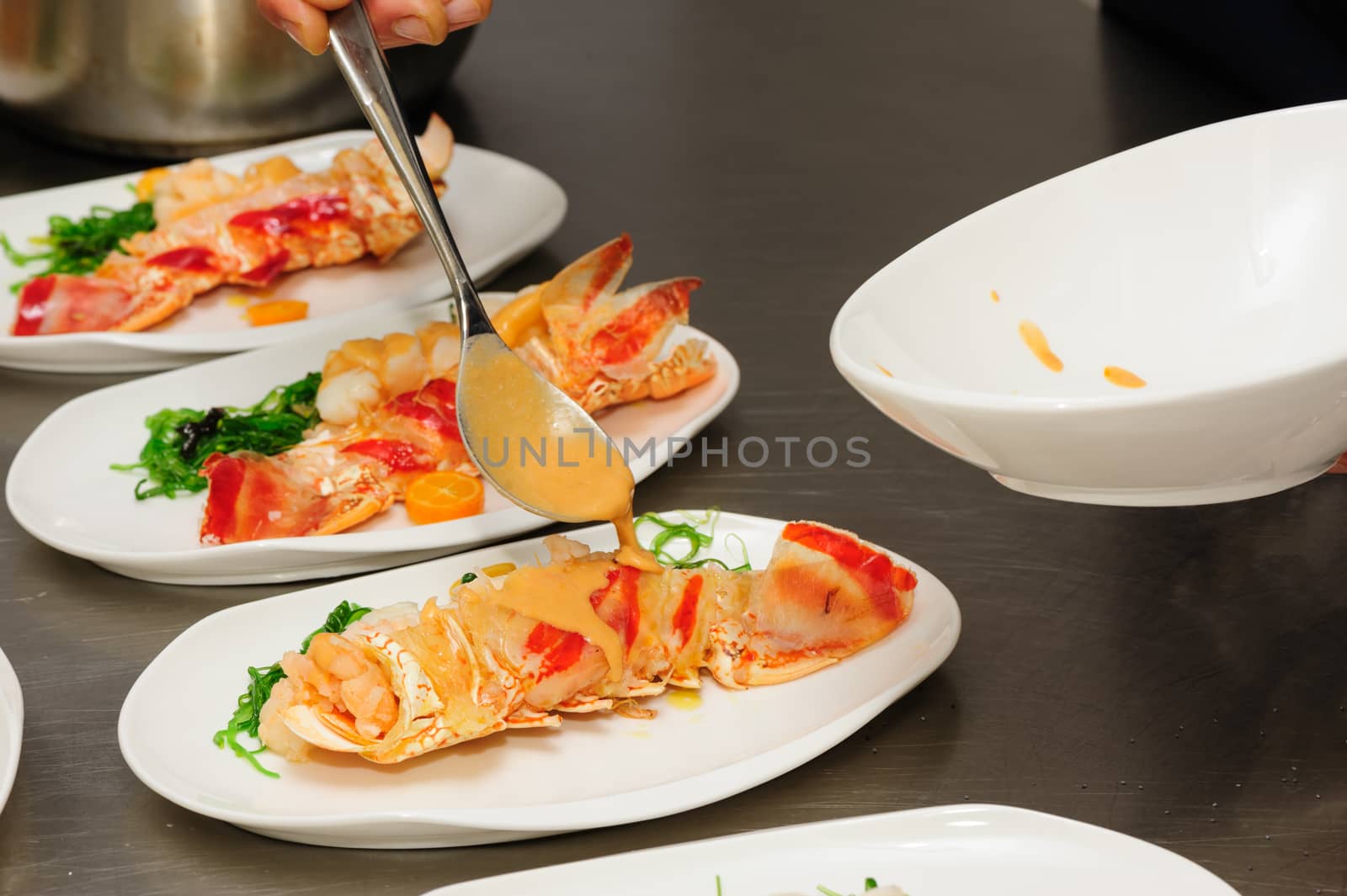 Decorating of prepared lobsters on plates, pouring the sauce