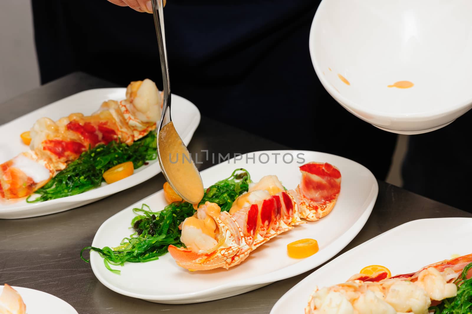 Decorating of prepared lobsters on plates, pouring the sauce