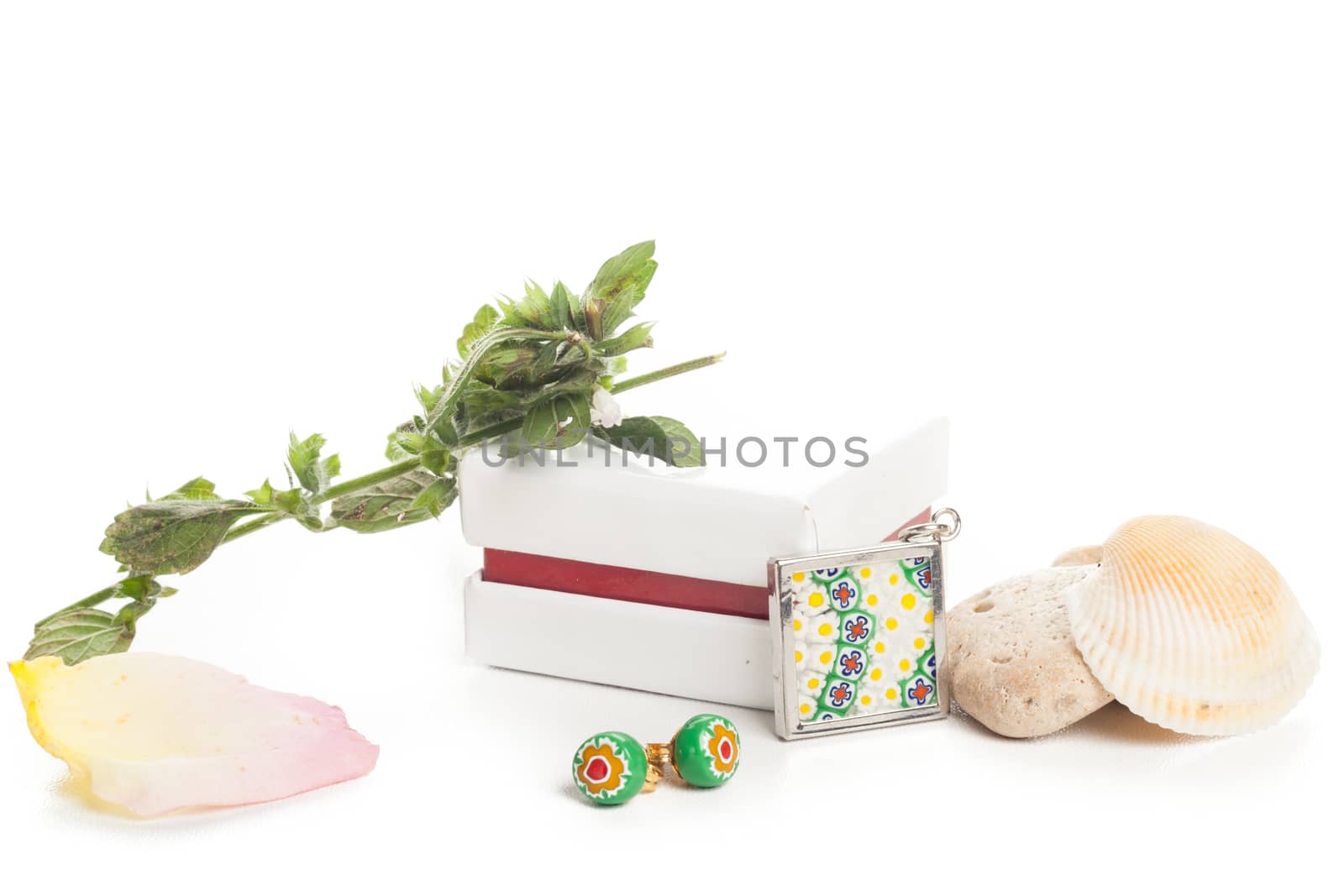 green earrings and medal with white box and stones and clam