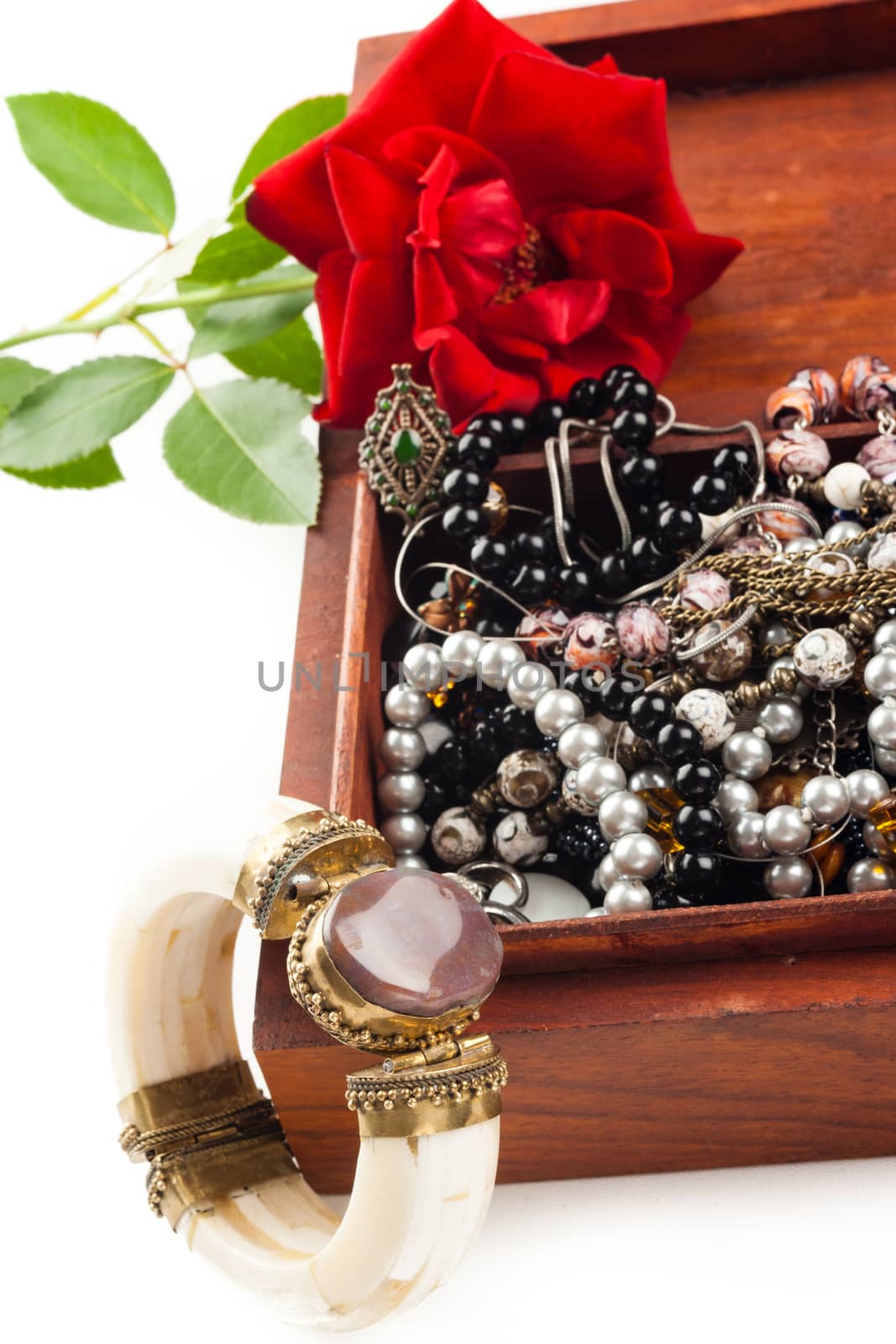 bunch of different color woman jewelry in wooden box and rose