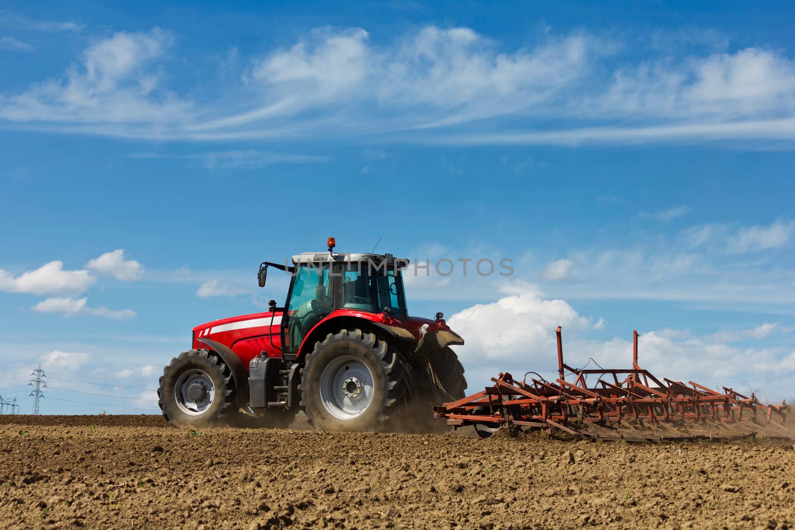 Farmer plowing the field. Cultivating tractor in the field. Red farm tractor with a plow in a farm field. Tractor and Plow